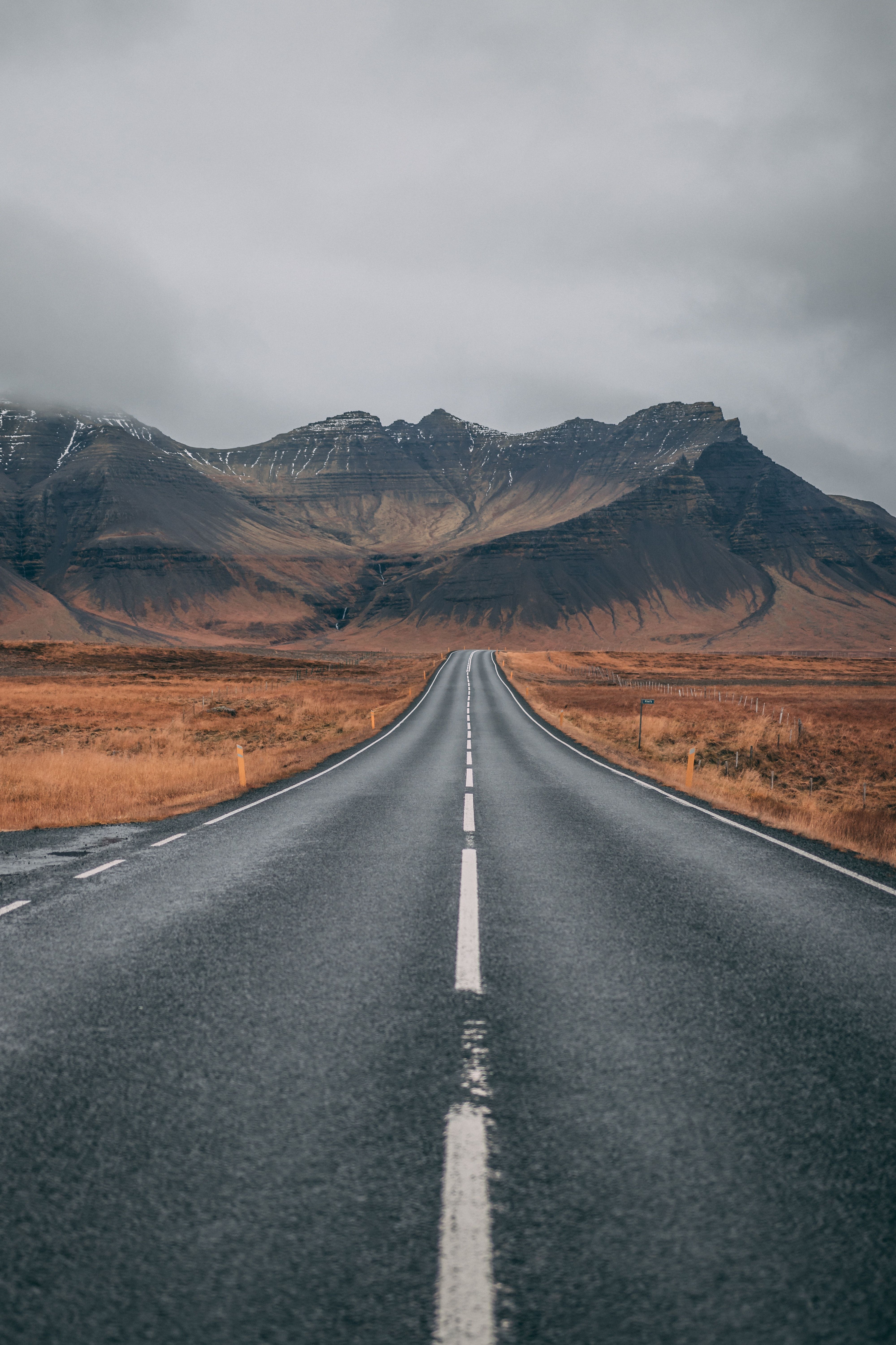 A long empty road with mountains in the background - Road