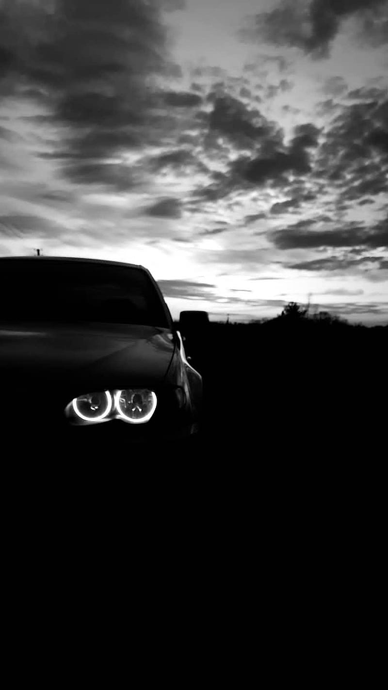 A car with its headlights on in a dark field - BMW