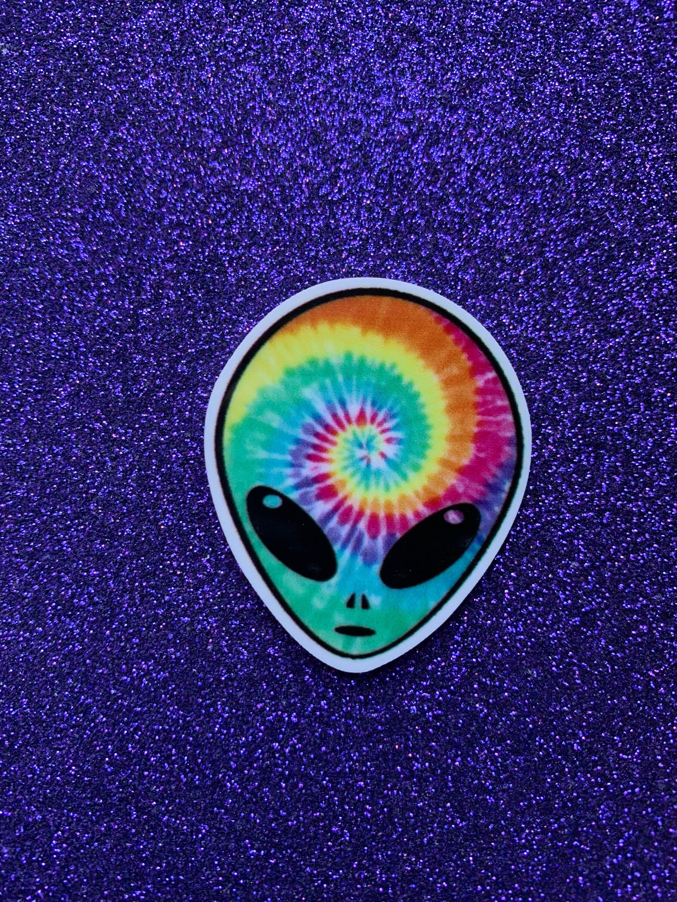 A sticker of a rainbow alien on a purple background - Alien