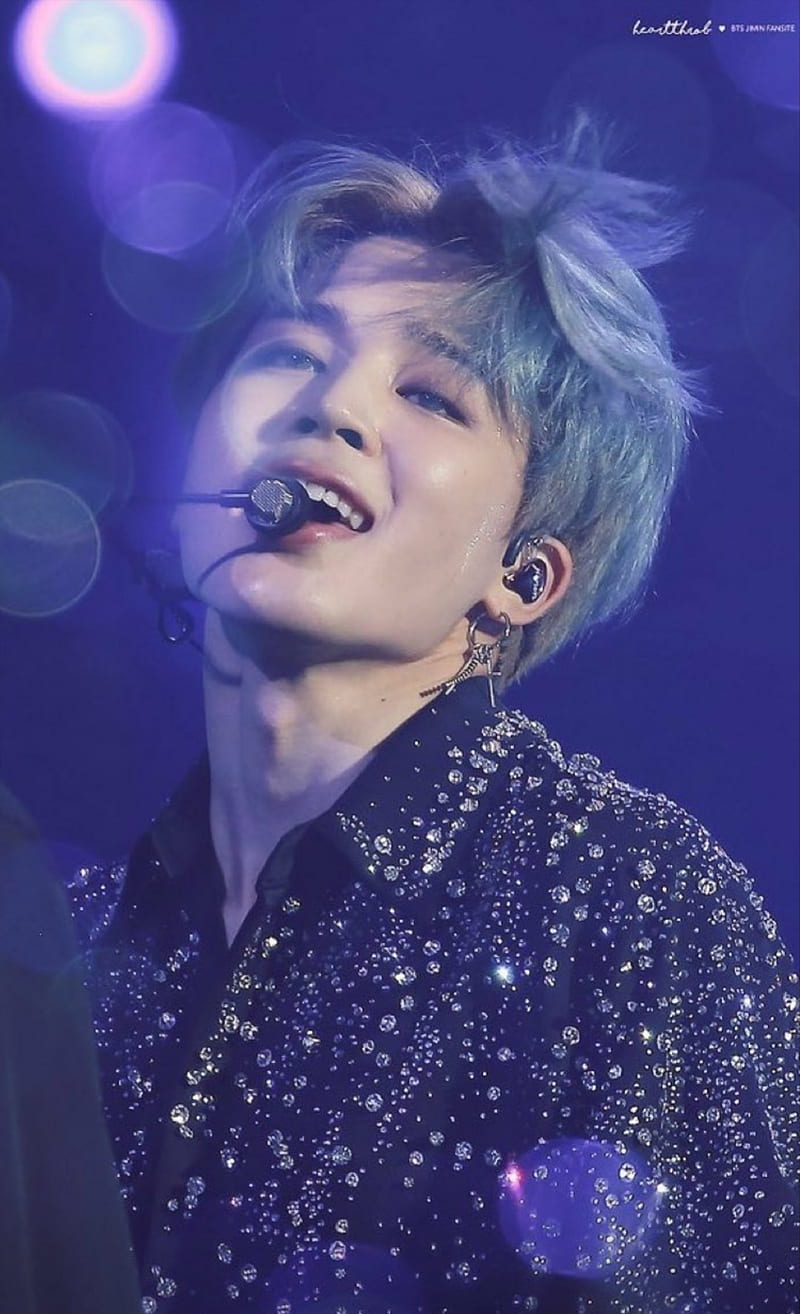 A person with blue hair is singing into the microphone - Jimin