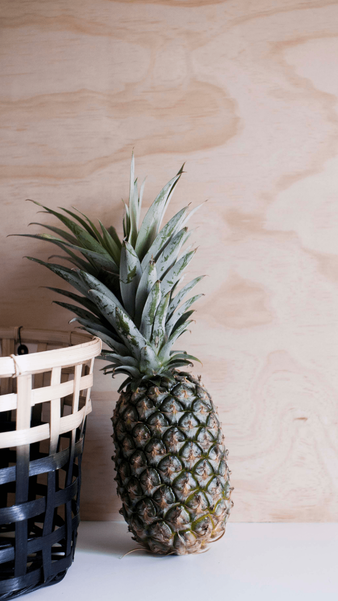 A pineapple and basket of fruit on the table - Pineapple