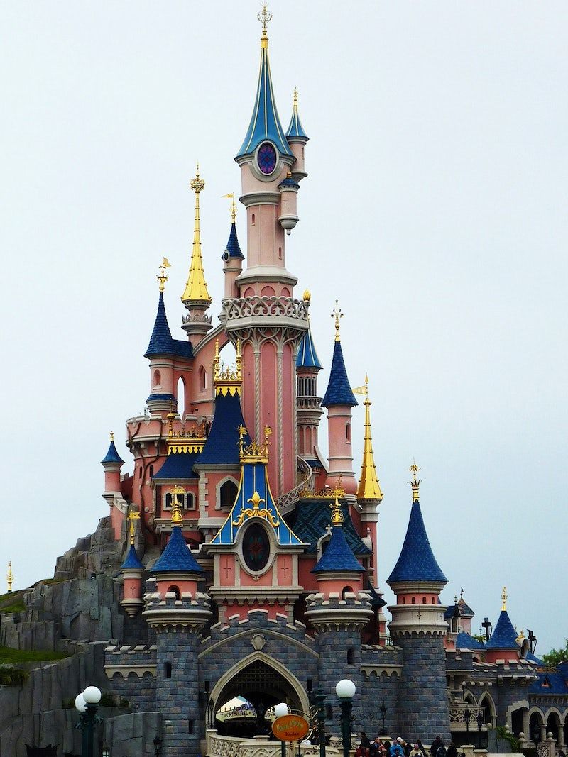 A pink and blue castle with gold spires. - Disneyland