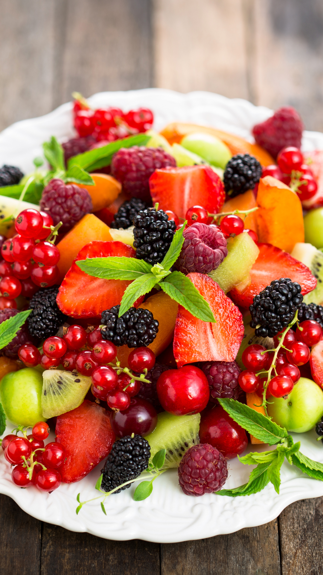 A plate of fruit and berries on top - Fruit