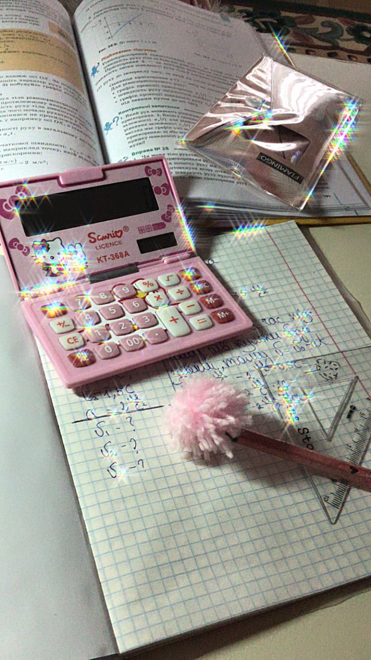 A pink calculator sits on a notebook with a math problem written on it. - Math