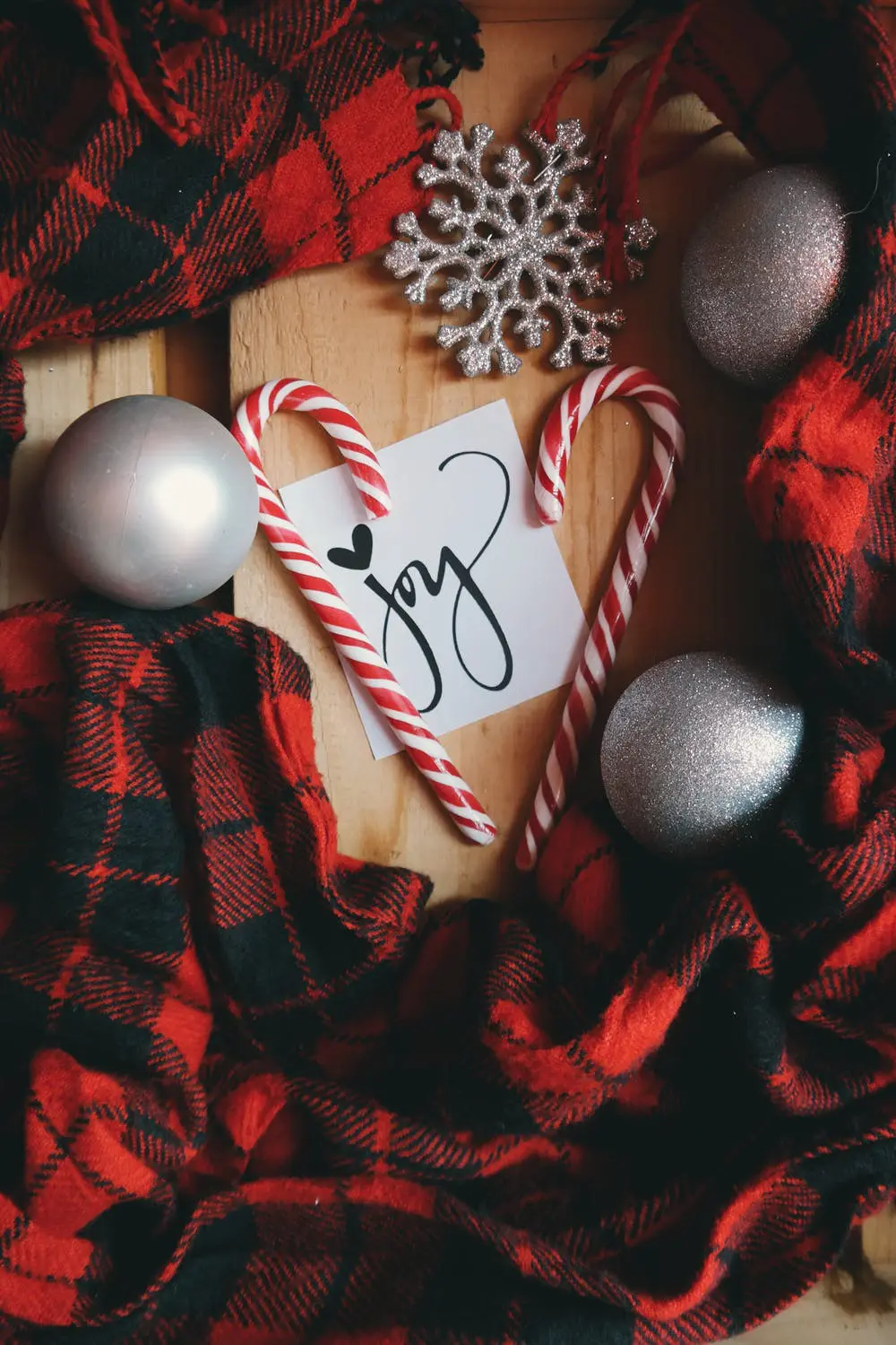 A red and black plaid blanket with candy canes, a snowflake, and a note that says 