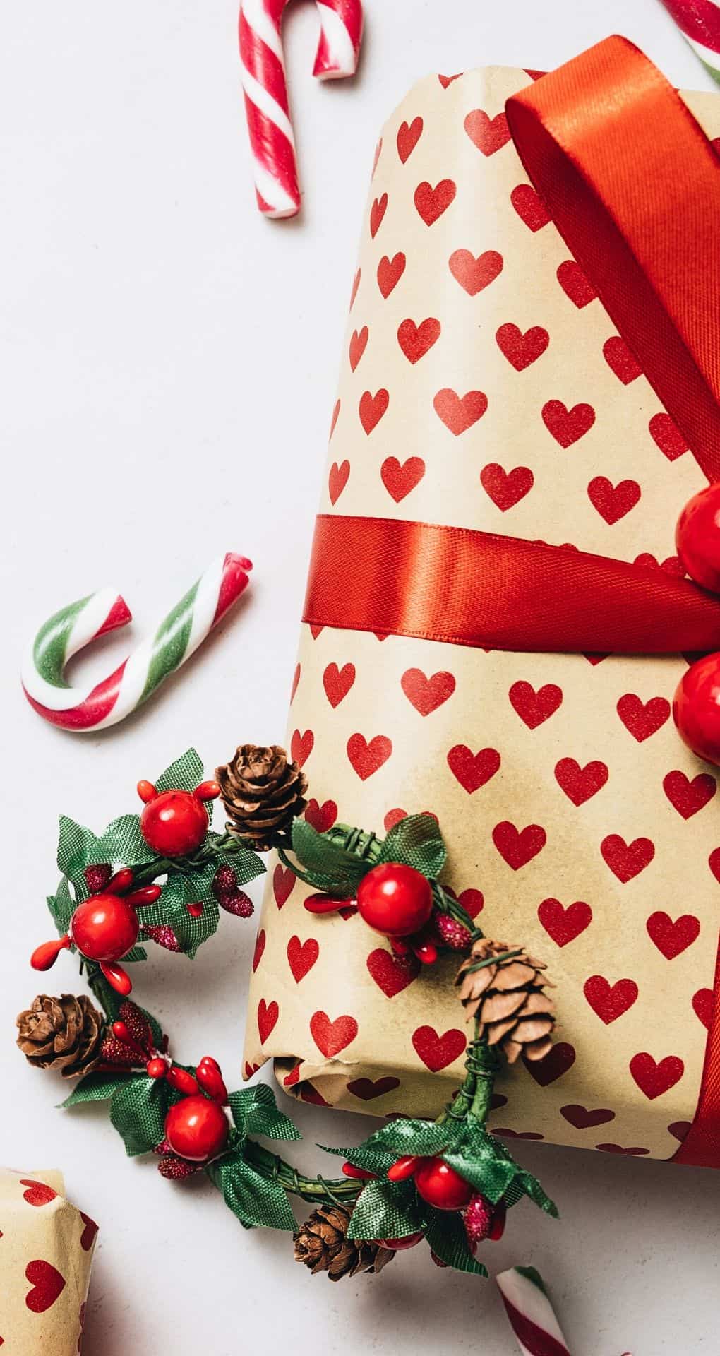 A present wrapped in brown paper with red hearts and a red ribbon. - Candy cane