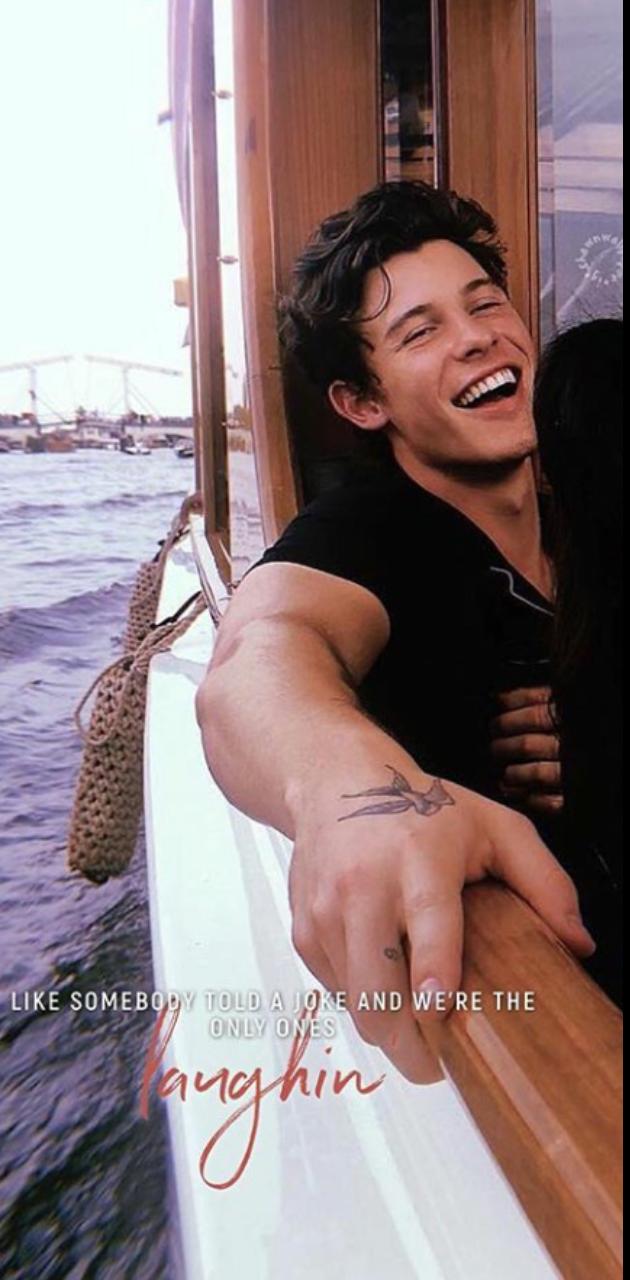 A man is smiling and holding his hand on the boat - Shawn Mendes