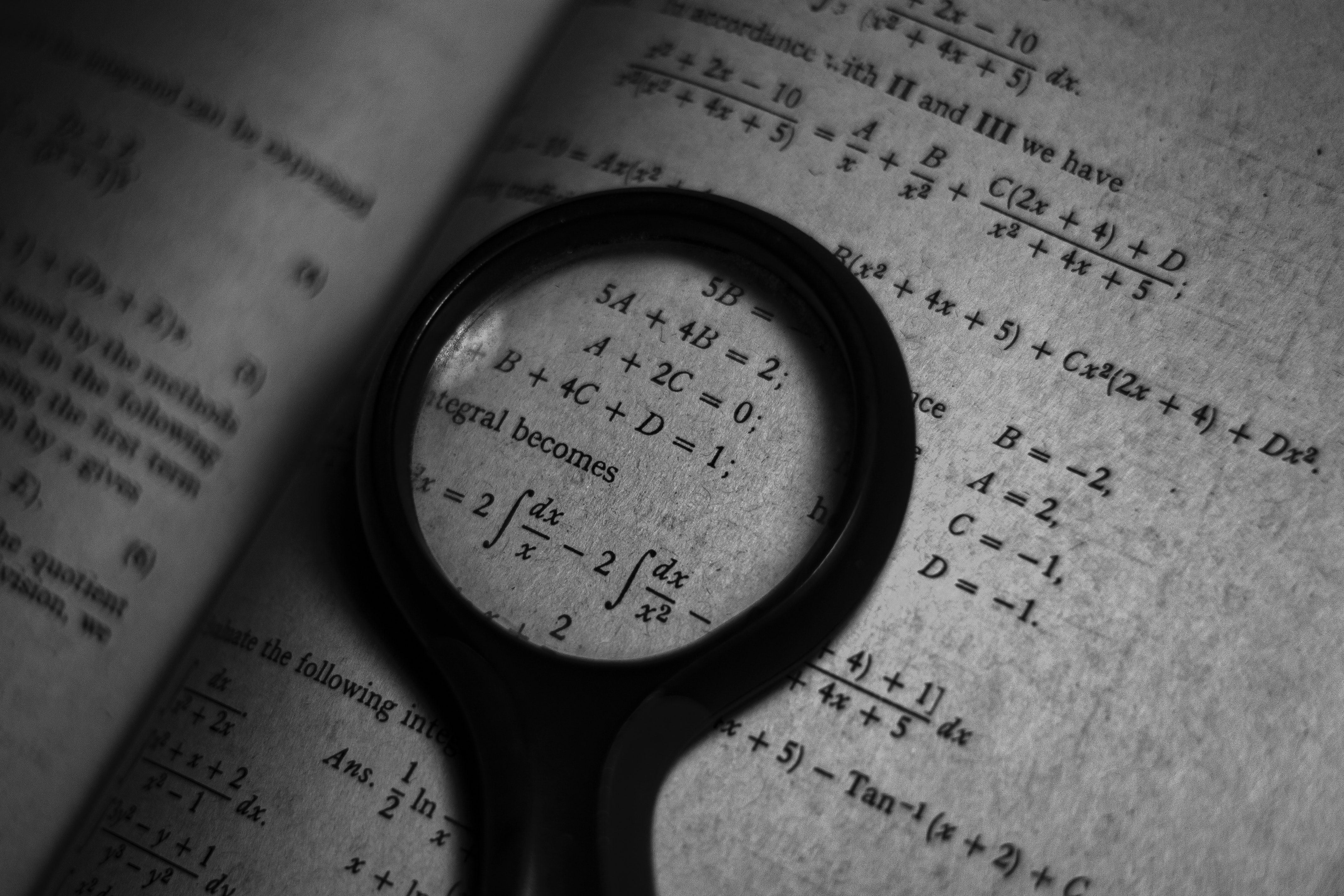 A magnifying glass is on top of an open book - Math