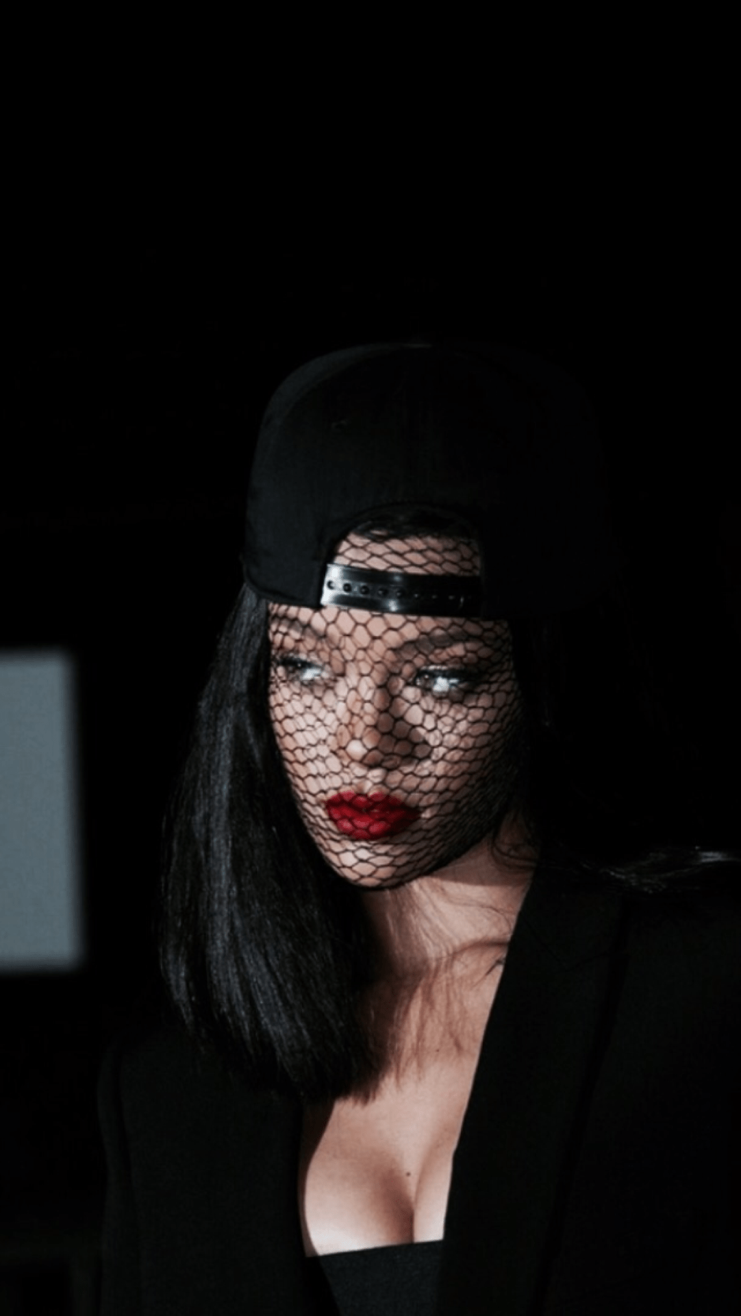 A woman with a black hat and veil covering her face. - Rihanna