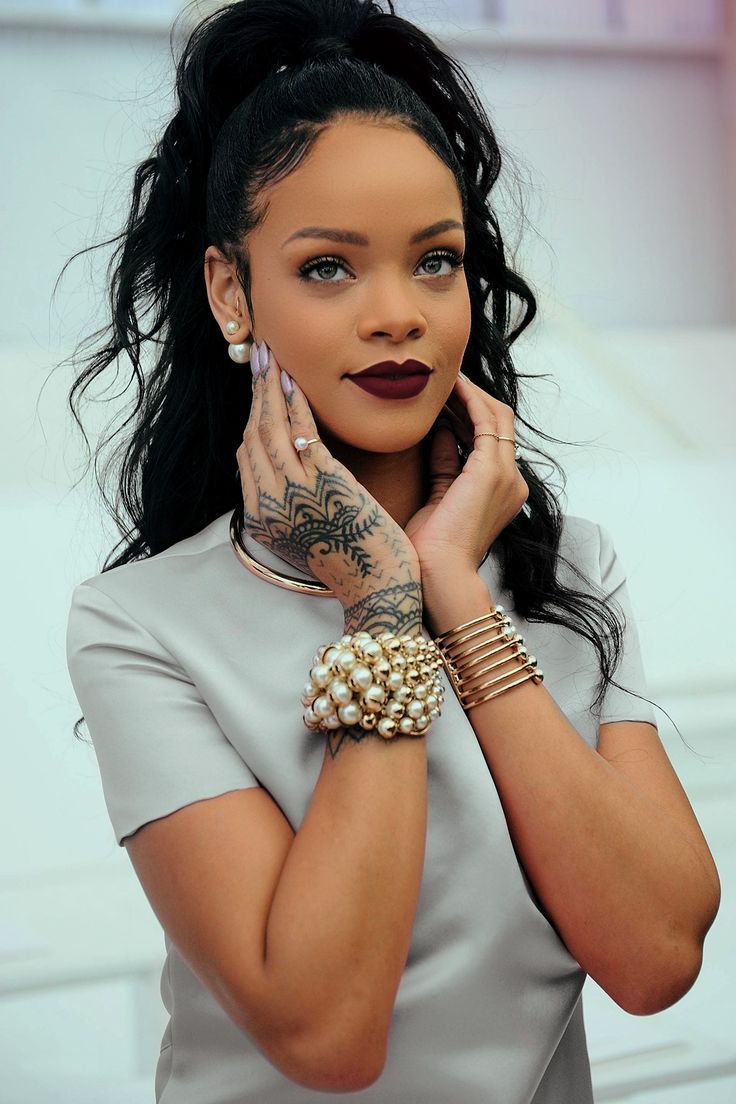 A woman with tattoos and jewelry posing for the camera - Rihanna