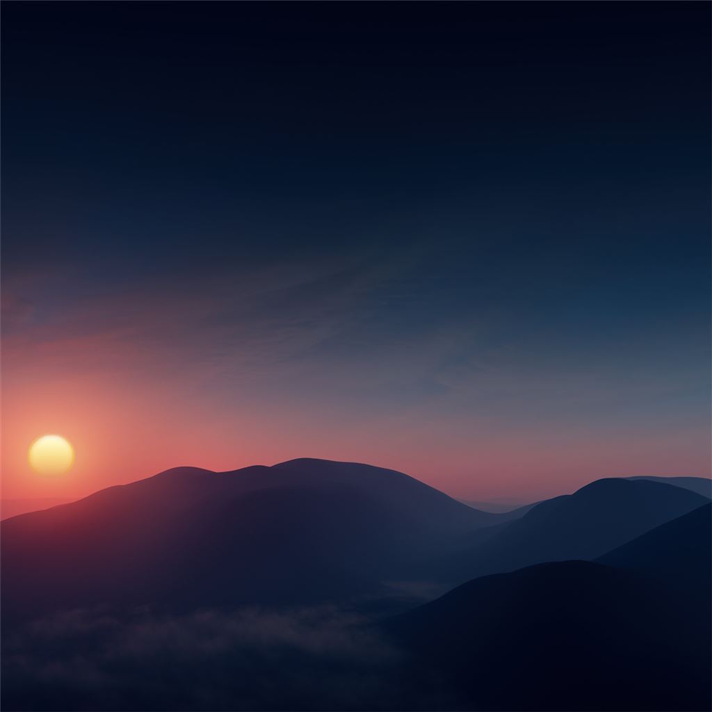A sunset over a mountain range with a sun setting behind the mountains - Sunrise