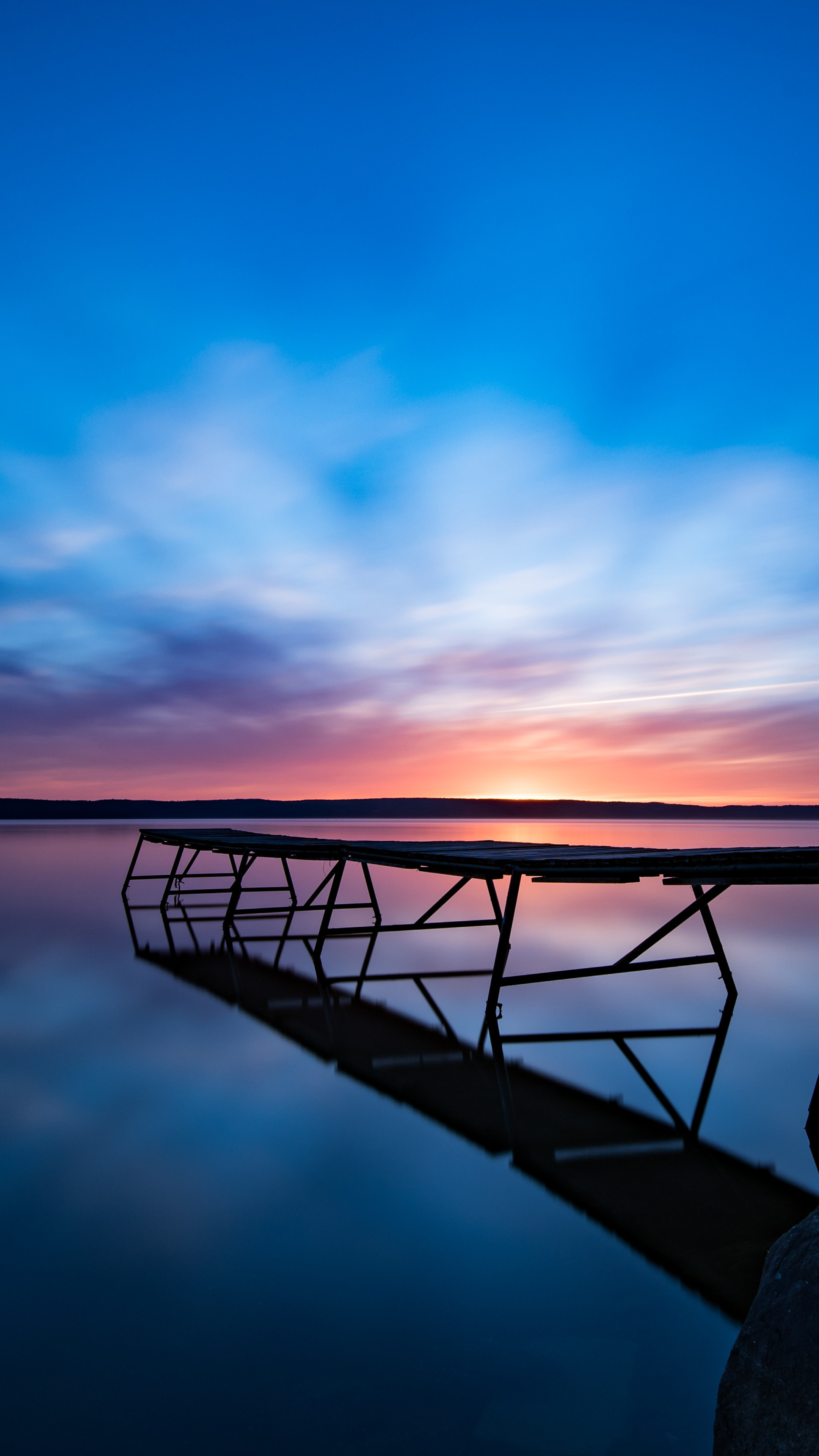 A long dock stretches out into a lake at sunset. - Sunrise