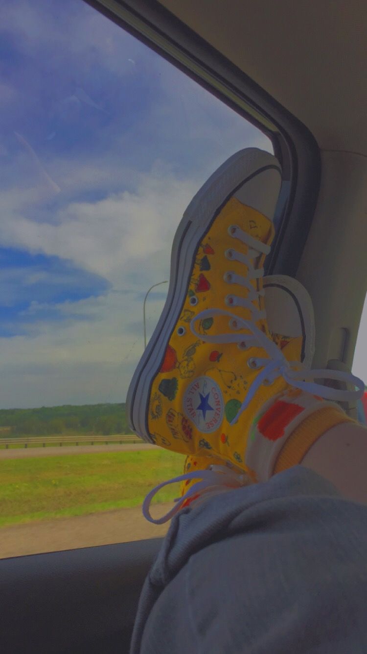 A person's feet with yellow shoes on them - Converse