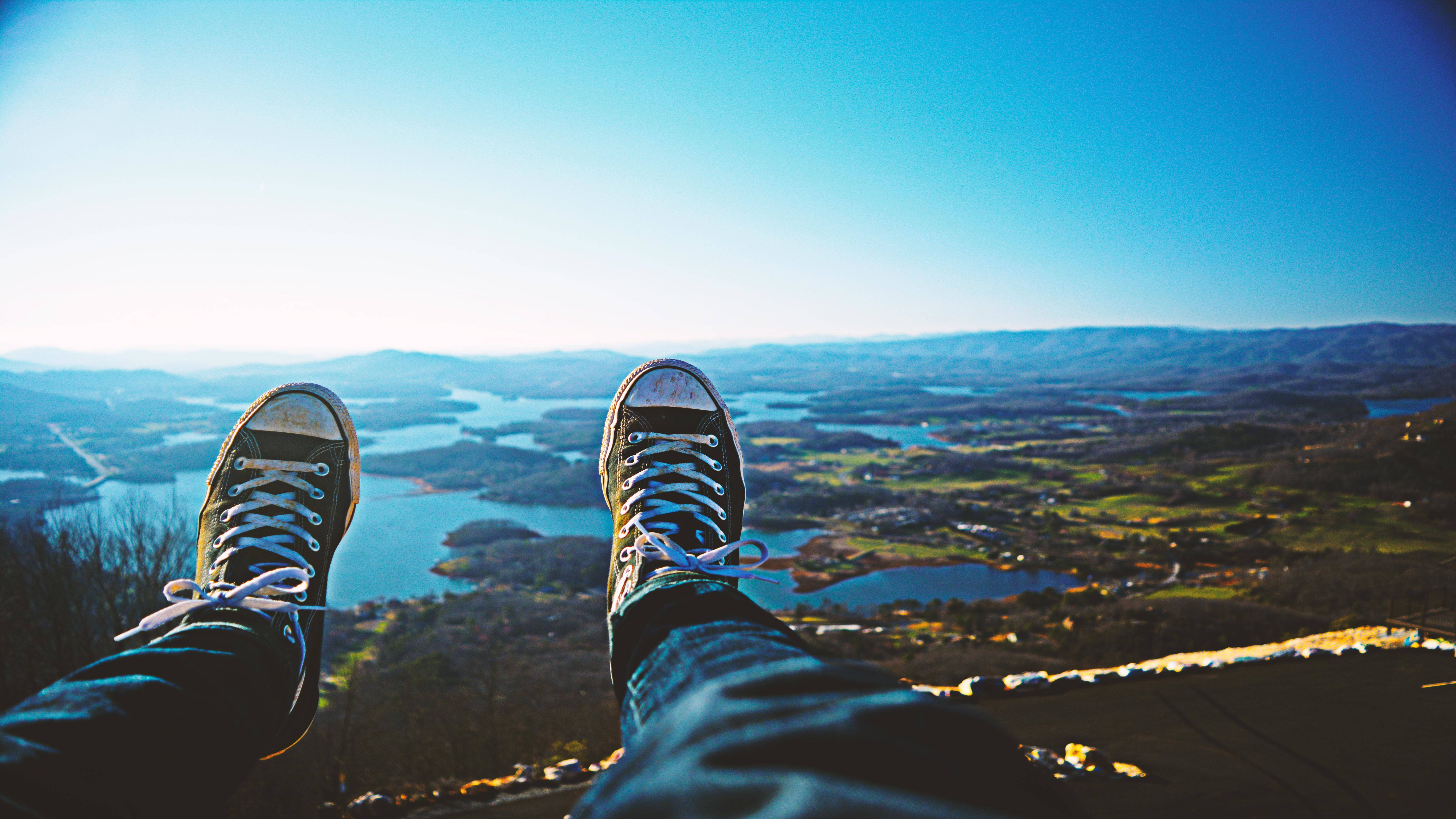 A person's feet are shown in the foreground with a beautiful mountain view in the background. - Converse