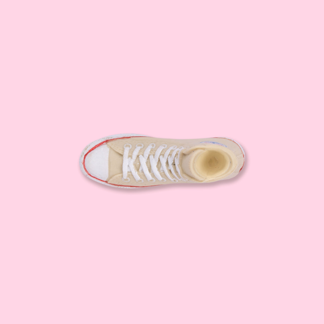 A sneaker with white laces on top of pink background - Converse