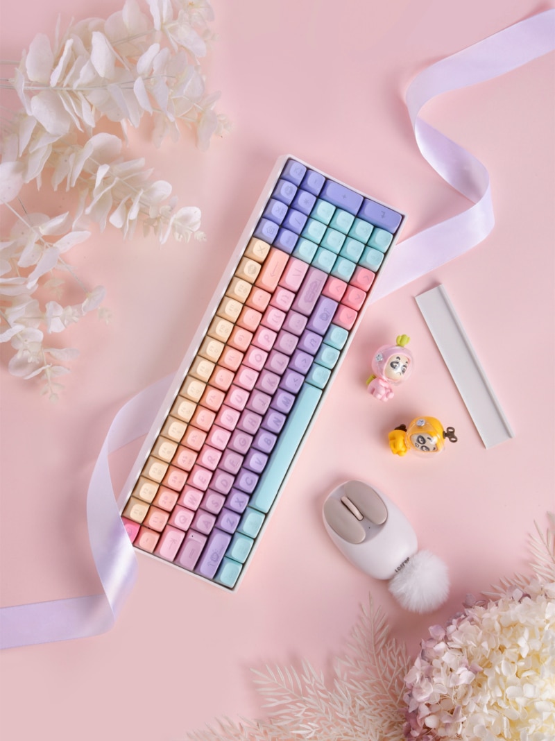 A keyboard with pastel colors is placed on a pink table. - Makeup