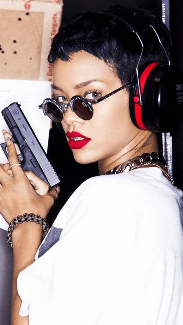 A woman with headphones and holding up her gun - Rihanna