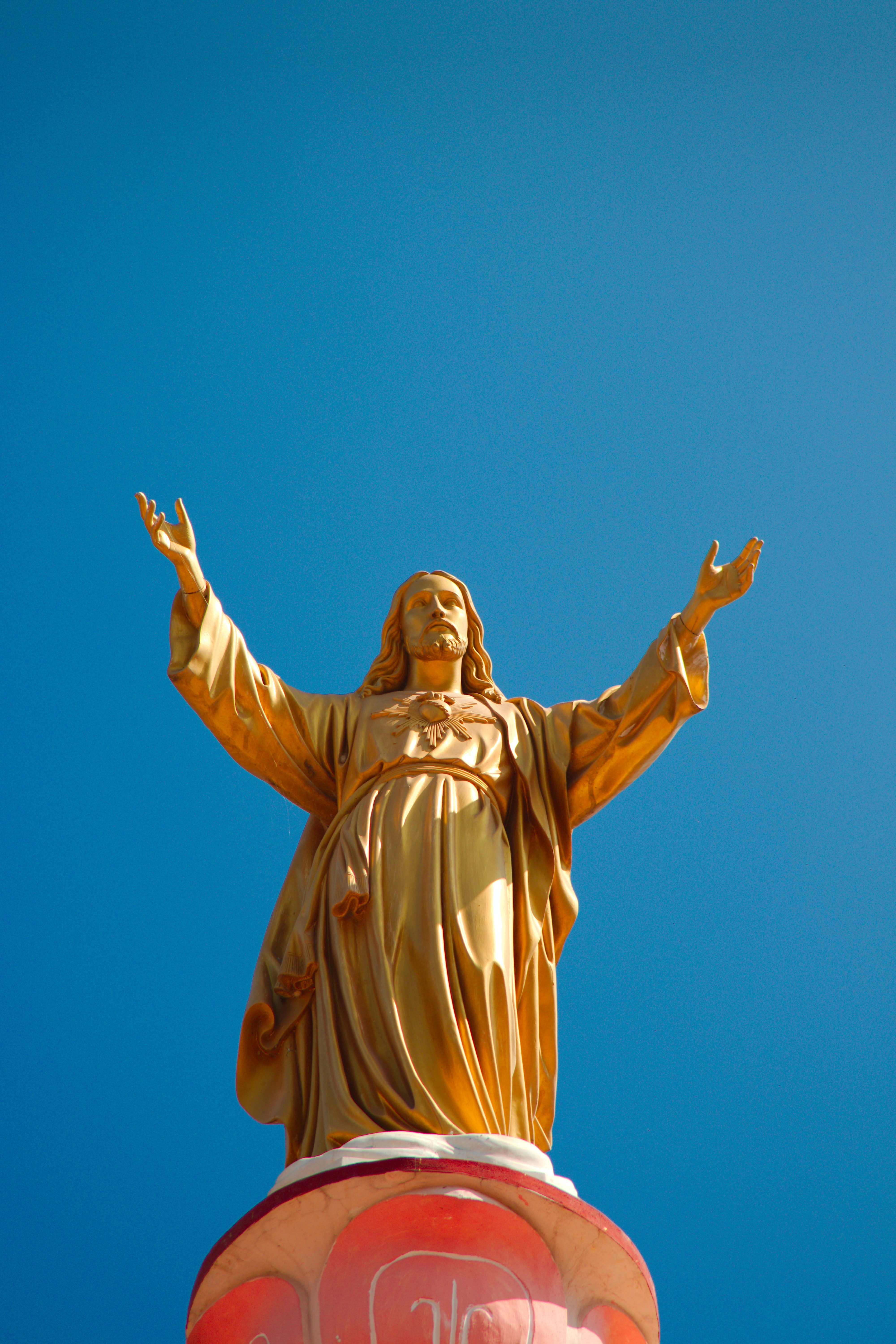 A golden statue of Jesus with his arms outstretched. - Jesus