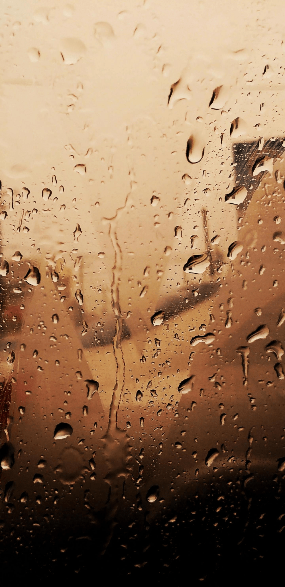 A photo of raindrops on a window with a brown background - Rain