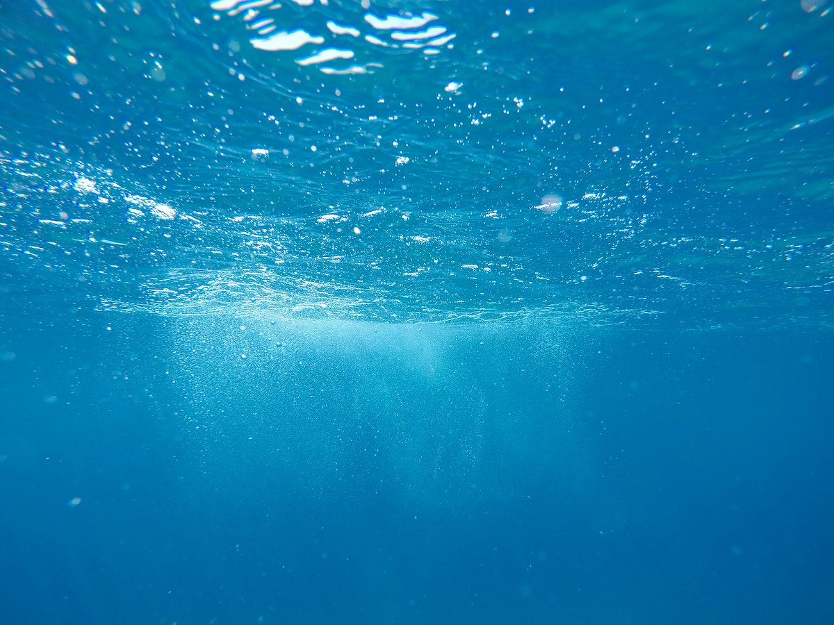 A picture of the ocean's surface, with the sun shining through the water. - Underwater