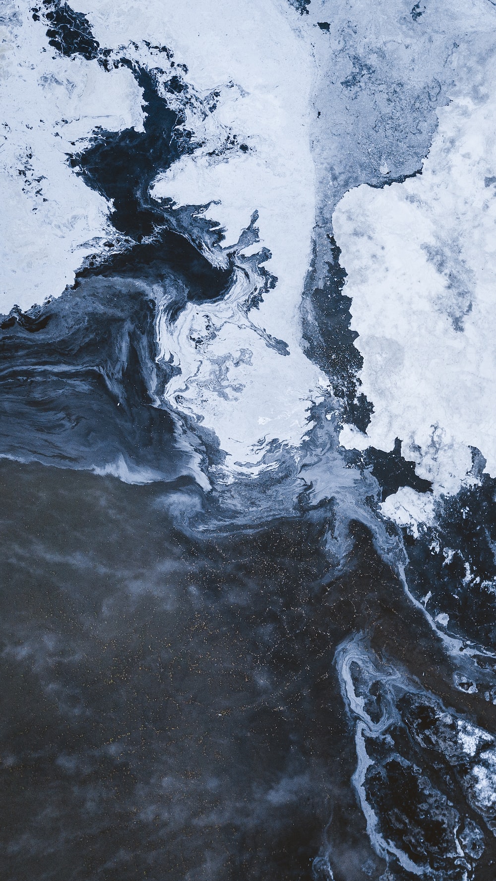 An aerial view of a body of water with ice and snow. - Marble
