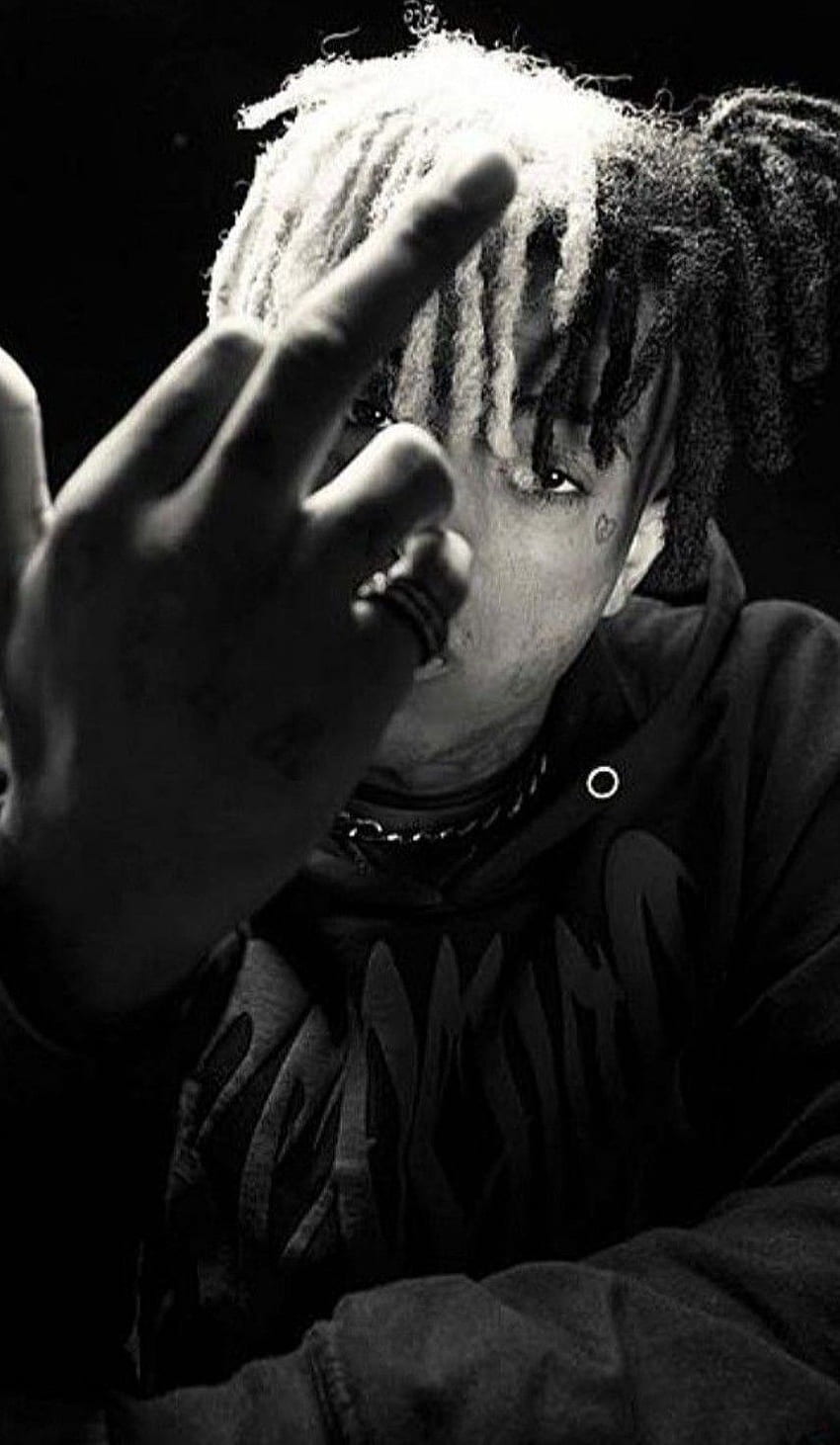 A black and white photo of Juice WRLD holding up his middle finger. - XXXTentacion