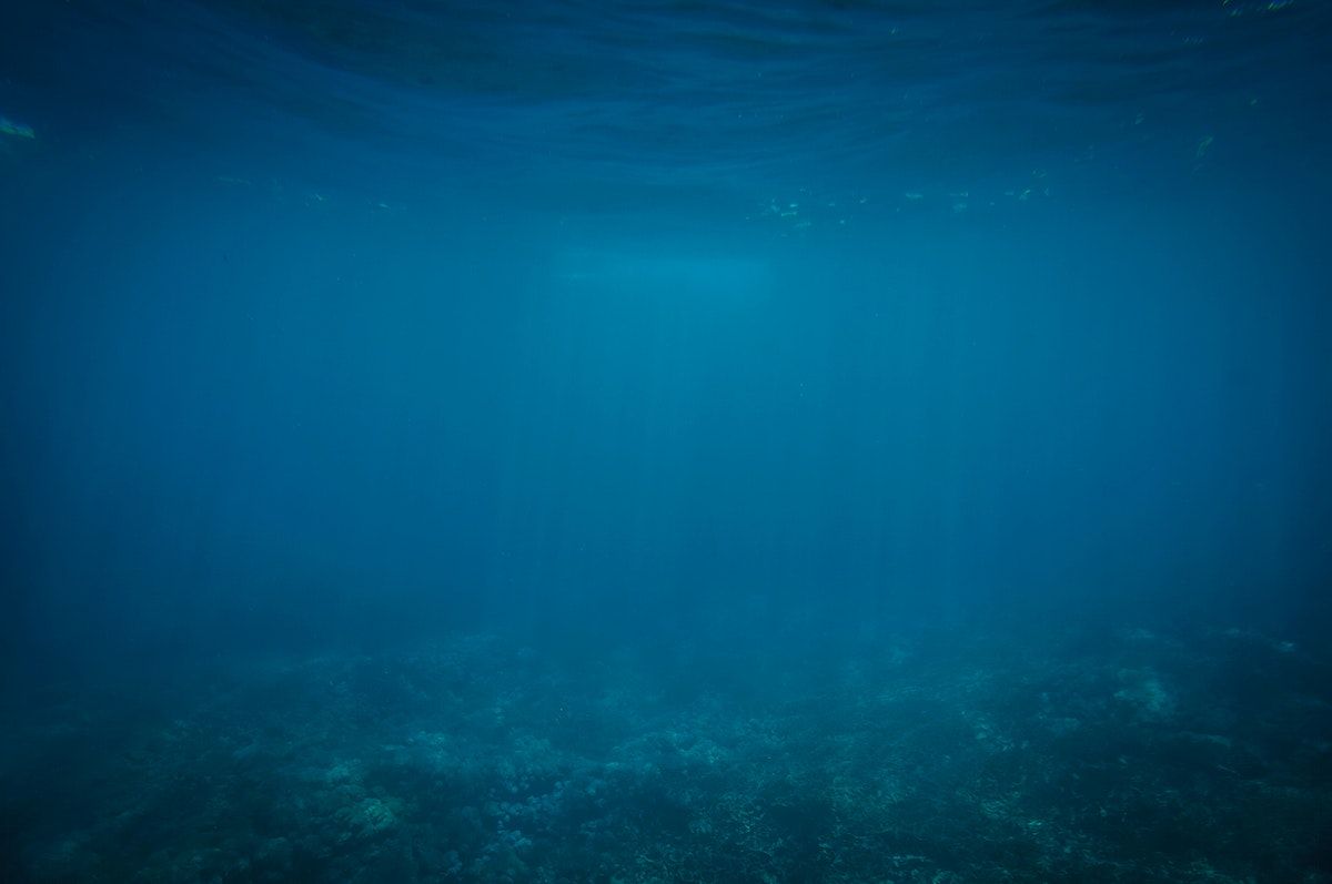 A deep blue sea with rocks visible at the bottom - Underwater
