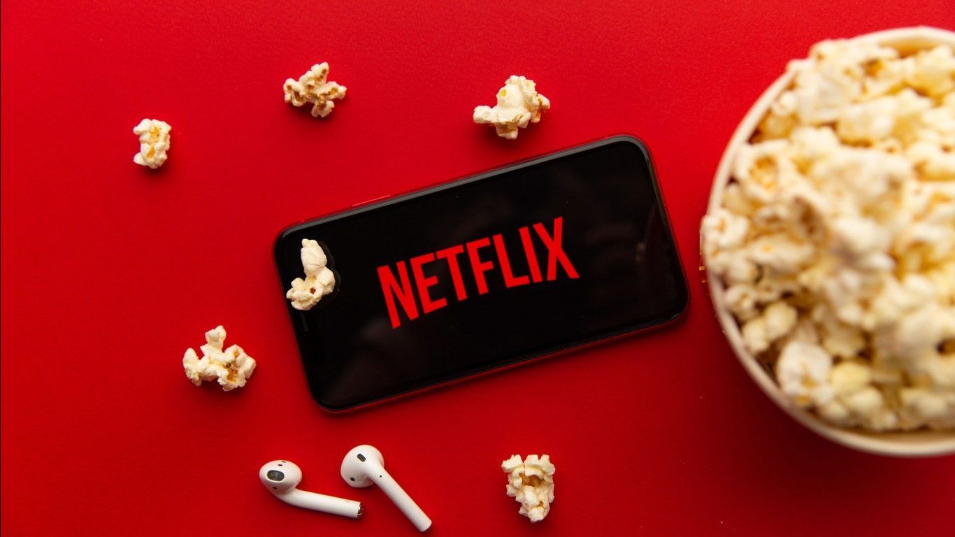 A phone with Netflix on it next to a bowl of popcorn - Netflix