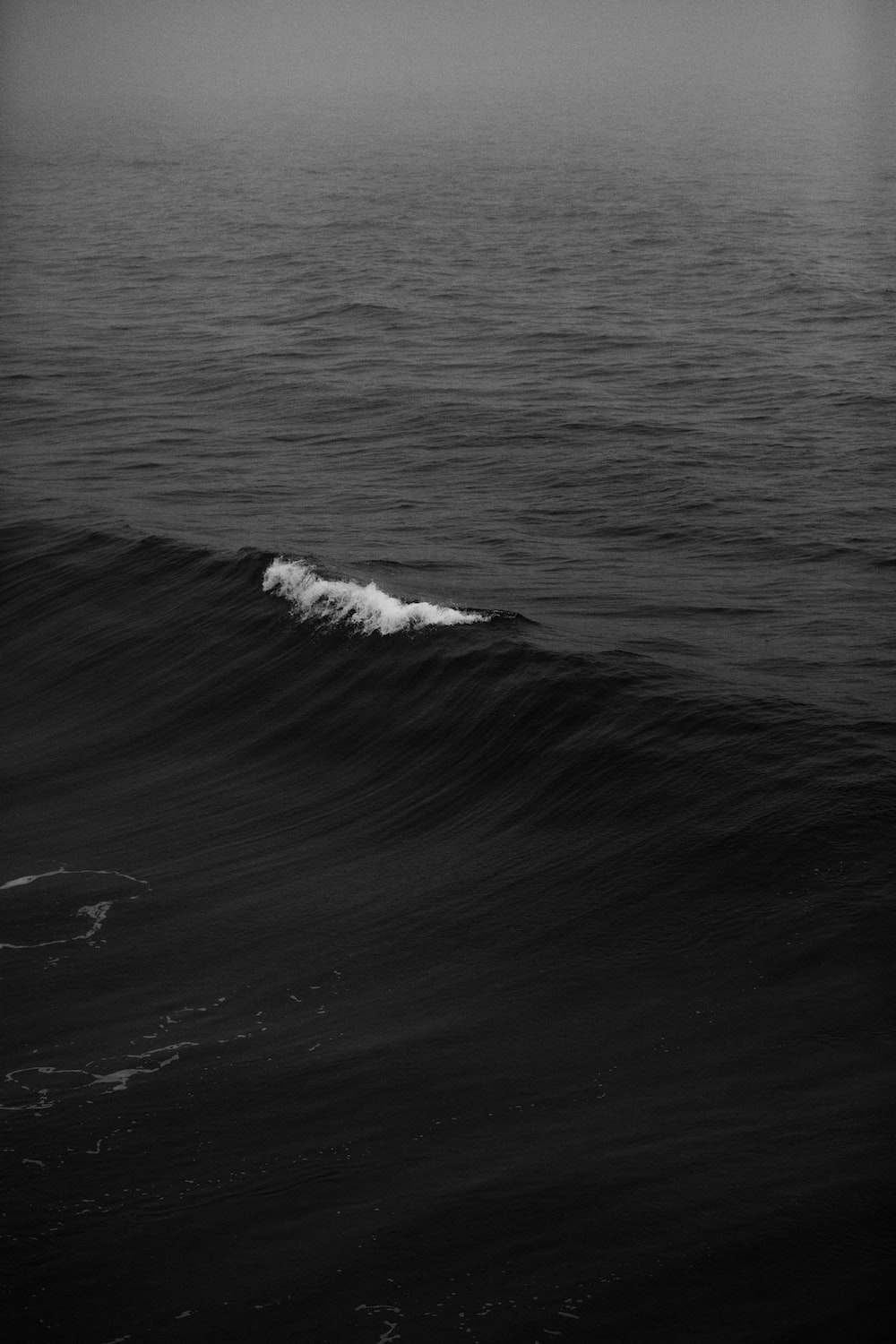 A black and white photo of a small wave in the ocean - Gray