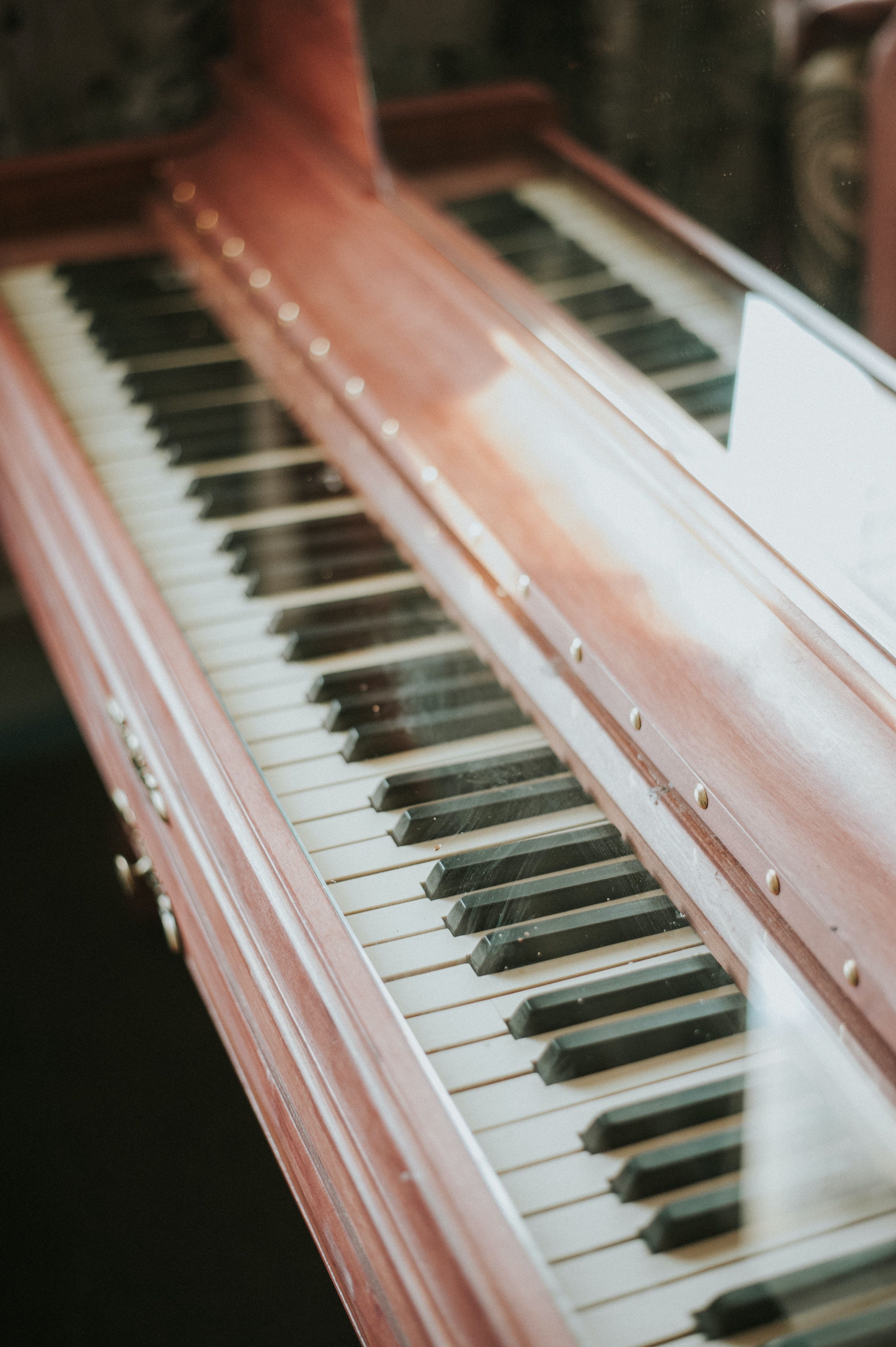 A close up of an old piano with a reflection of a person in the glass. - Piano