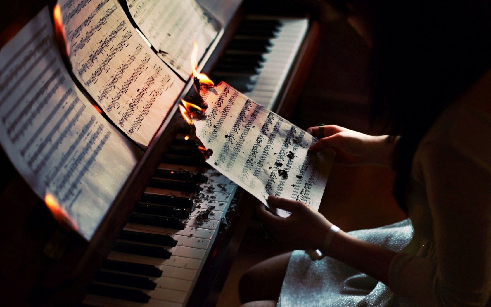 A woman burning sheet music over a piano. - Piano
