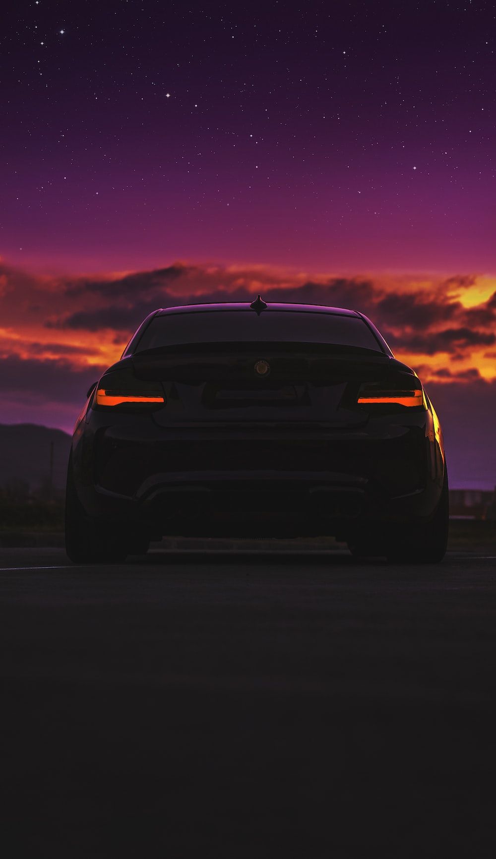 The back of a car on a road with a purple sky in the background - BMW