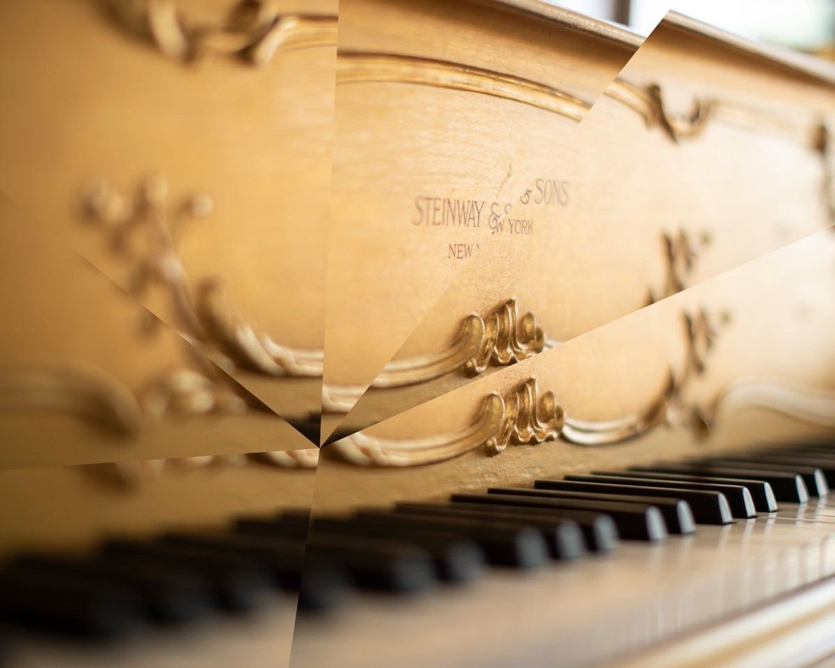 A Steinway piano in a room with the light shining on it. - Piano