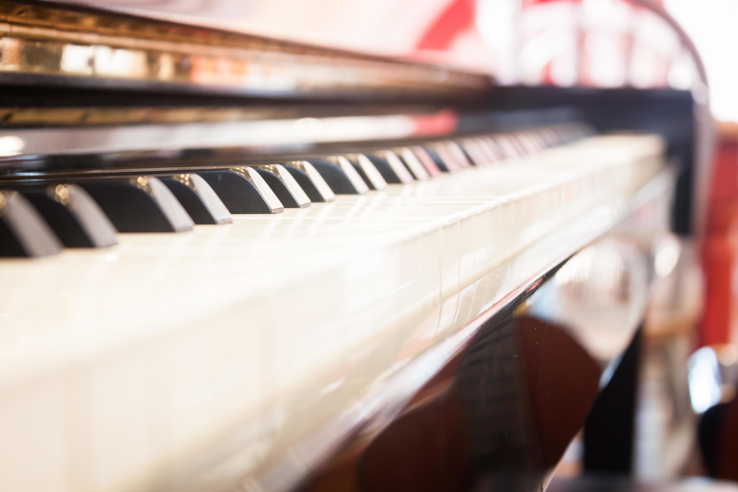 A close up of a piano keyboard with a red wall in the background. - Piano