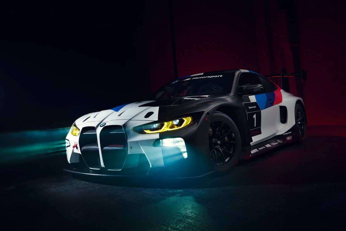 A bmw racing car is lit up in the dark - BMW