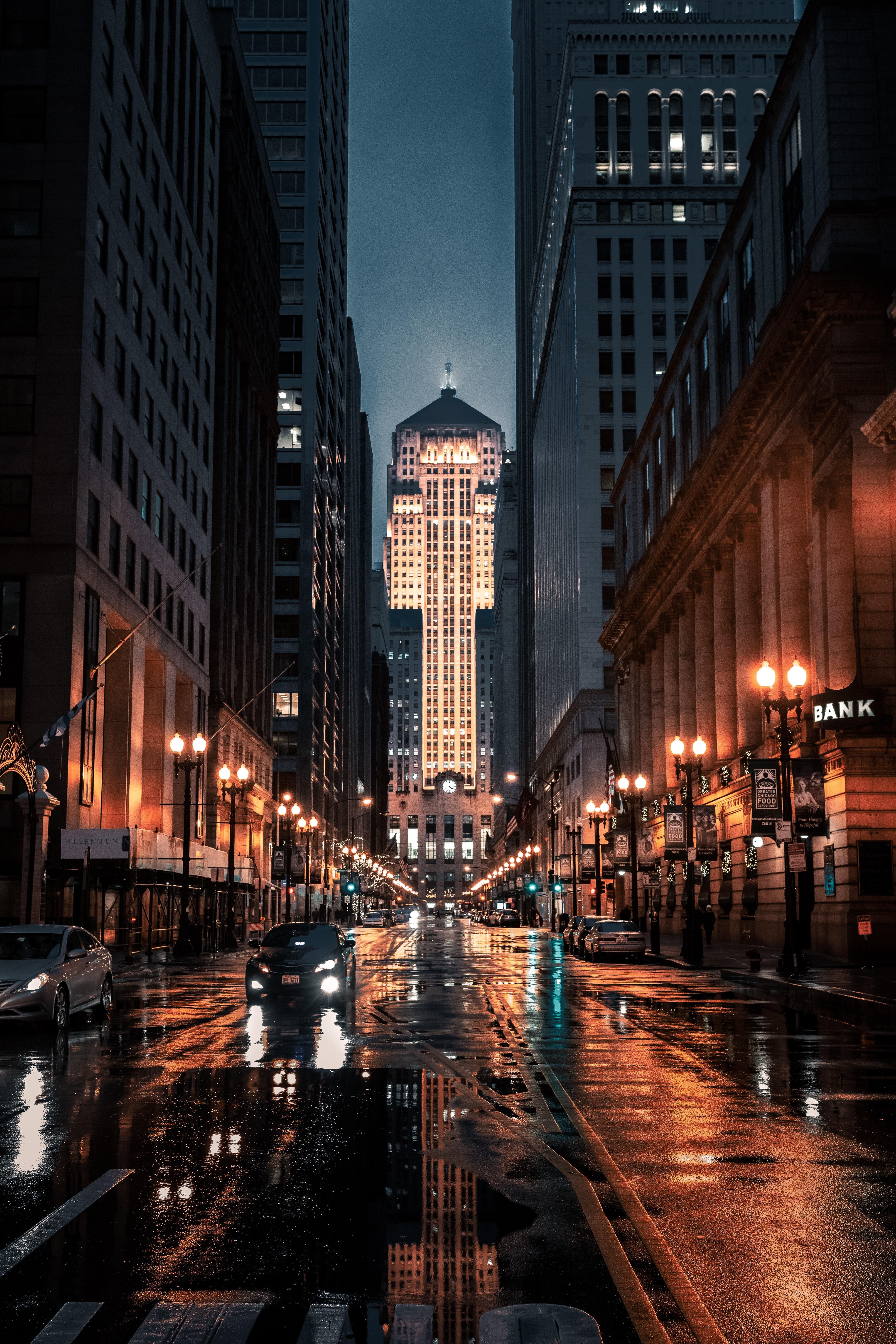 A street at night with a tall building lit up in the background. - Chicago