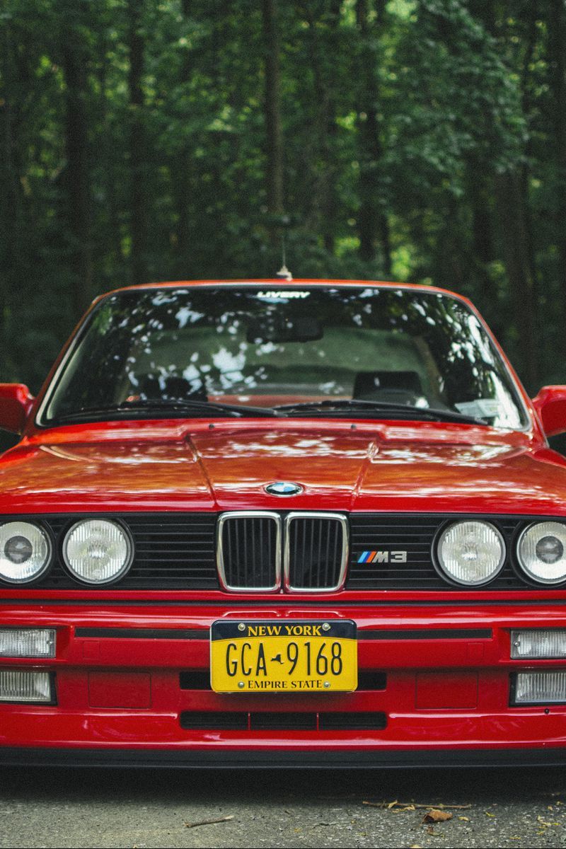 A red bmw car parked on the side of road - BMW