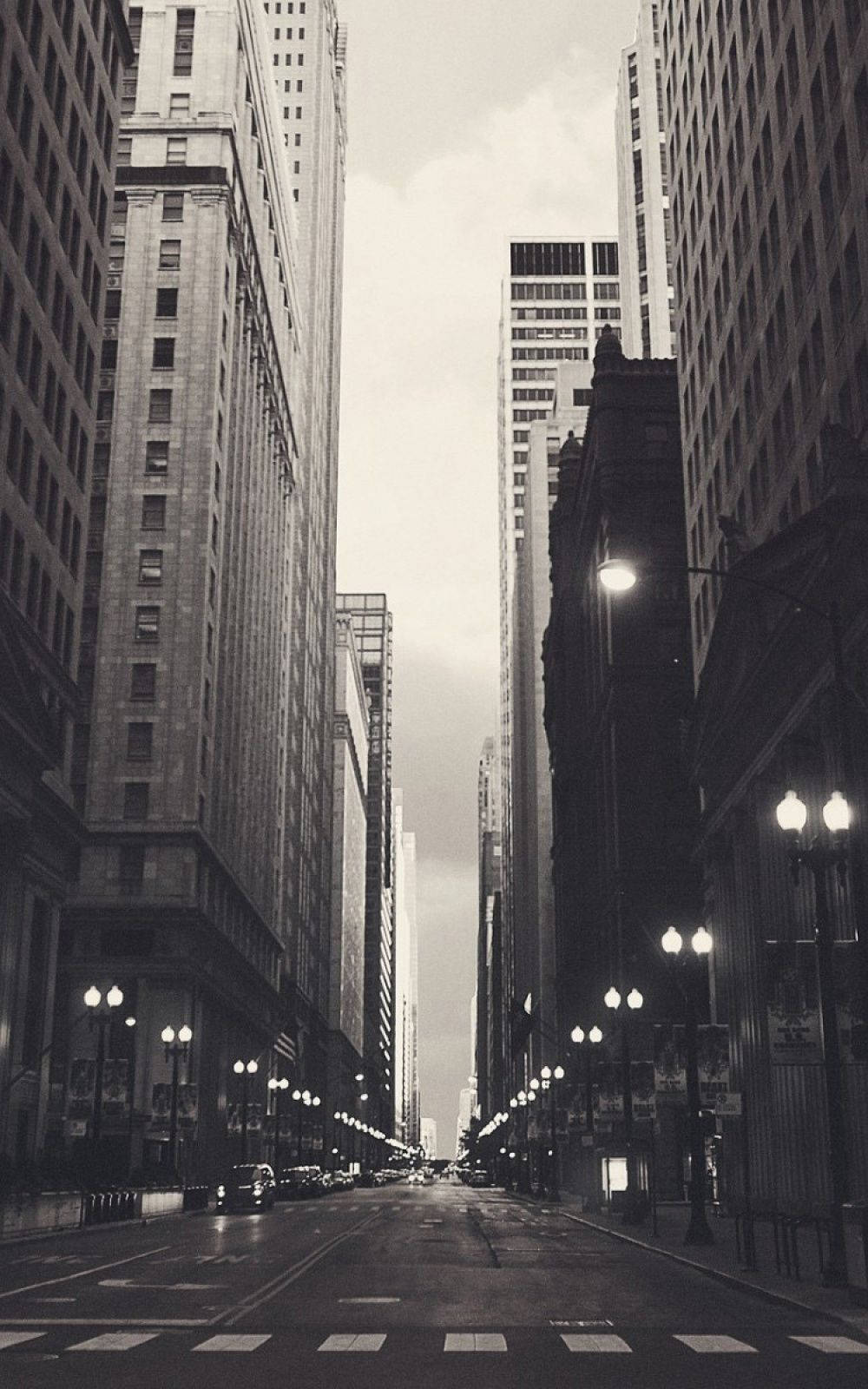 A black and white photo of a city street with tall buildings on either side. - Chicago