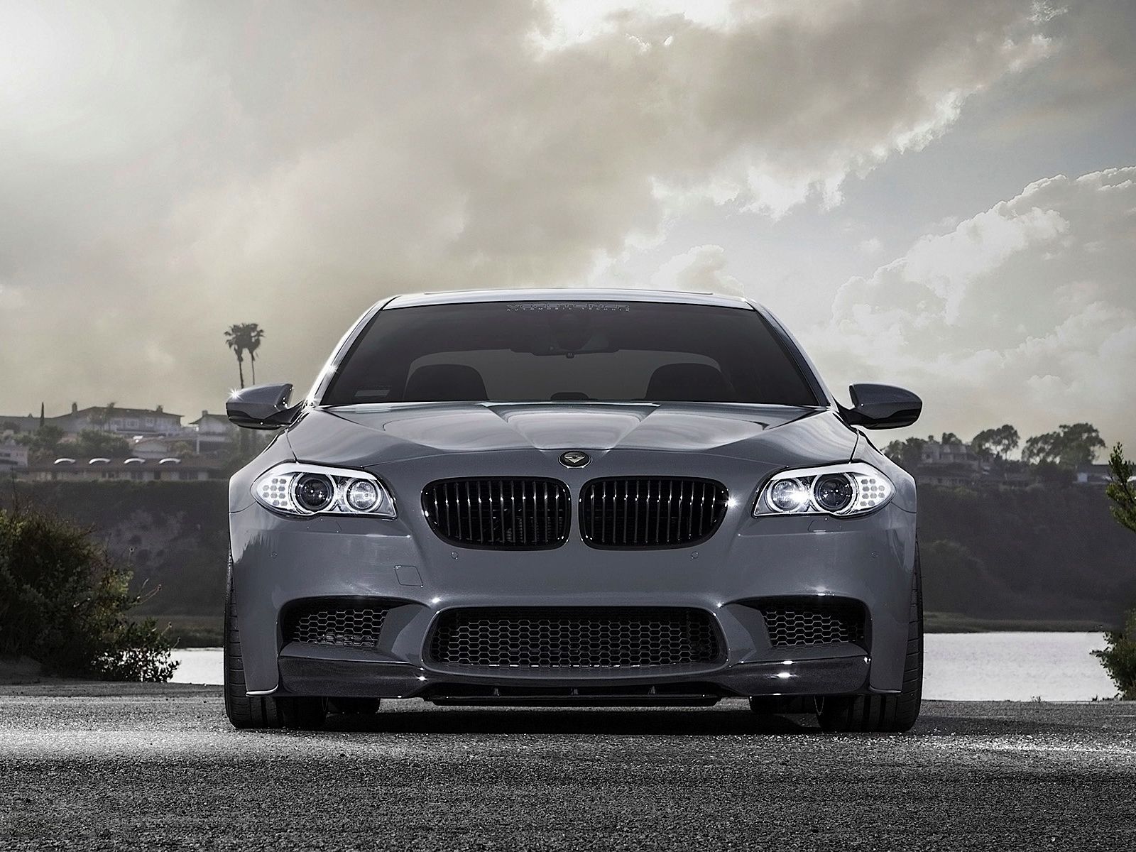 A grey 2013 BMW M5 is parked on the side of the road. - BMW