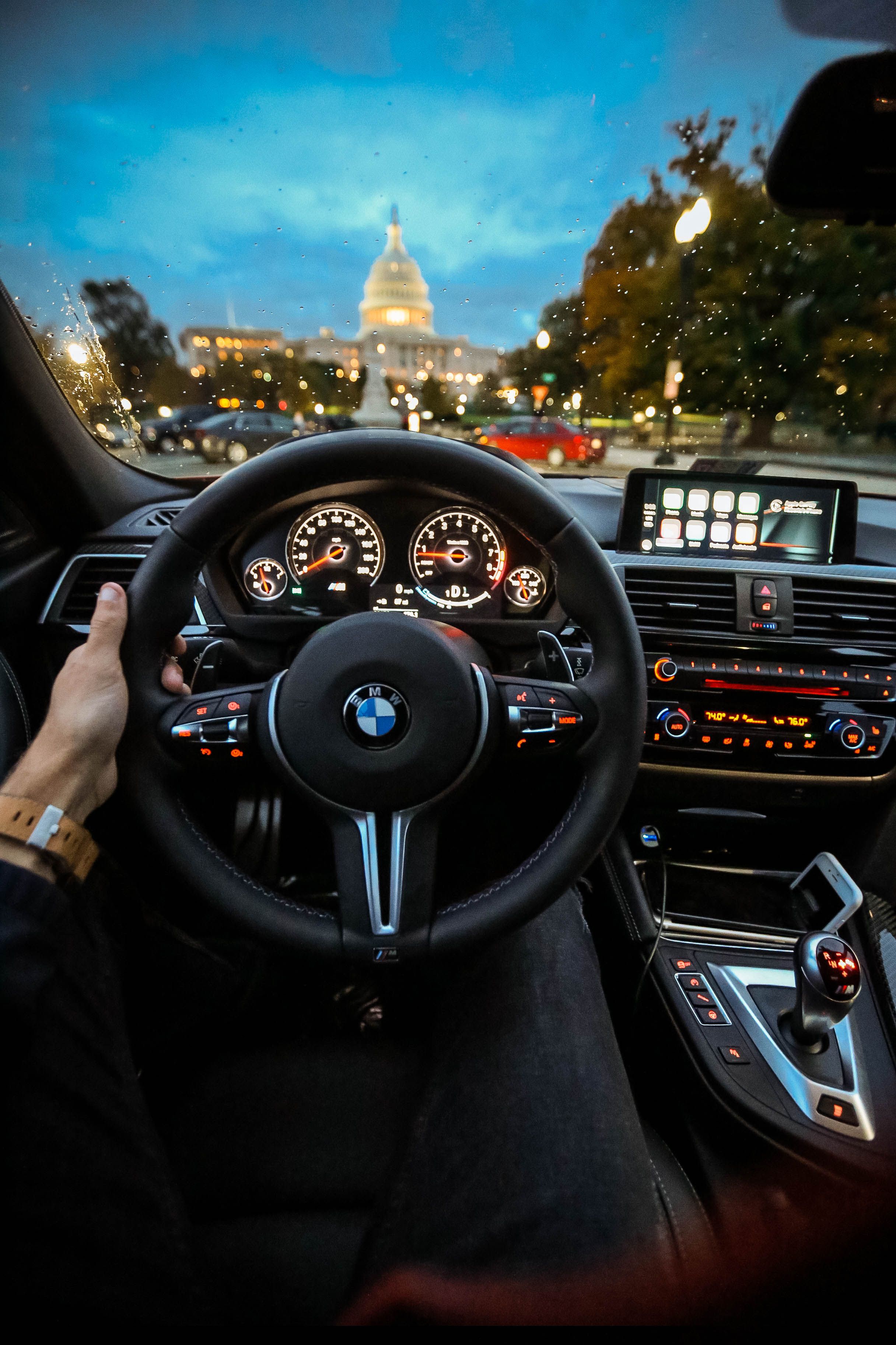 A man driving a car with the capitol building in the background. - BMW