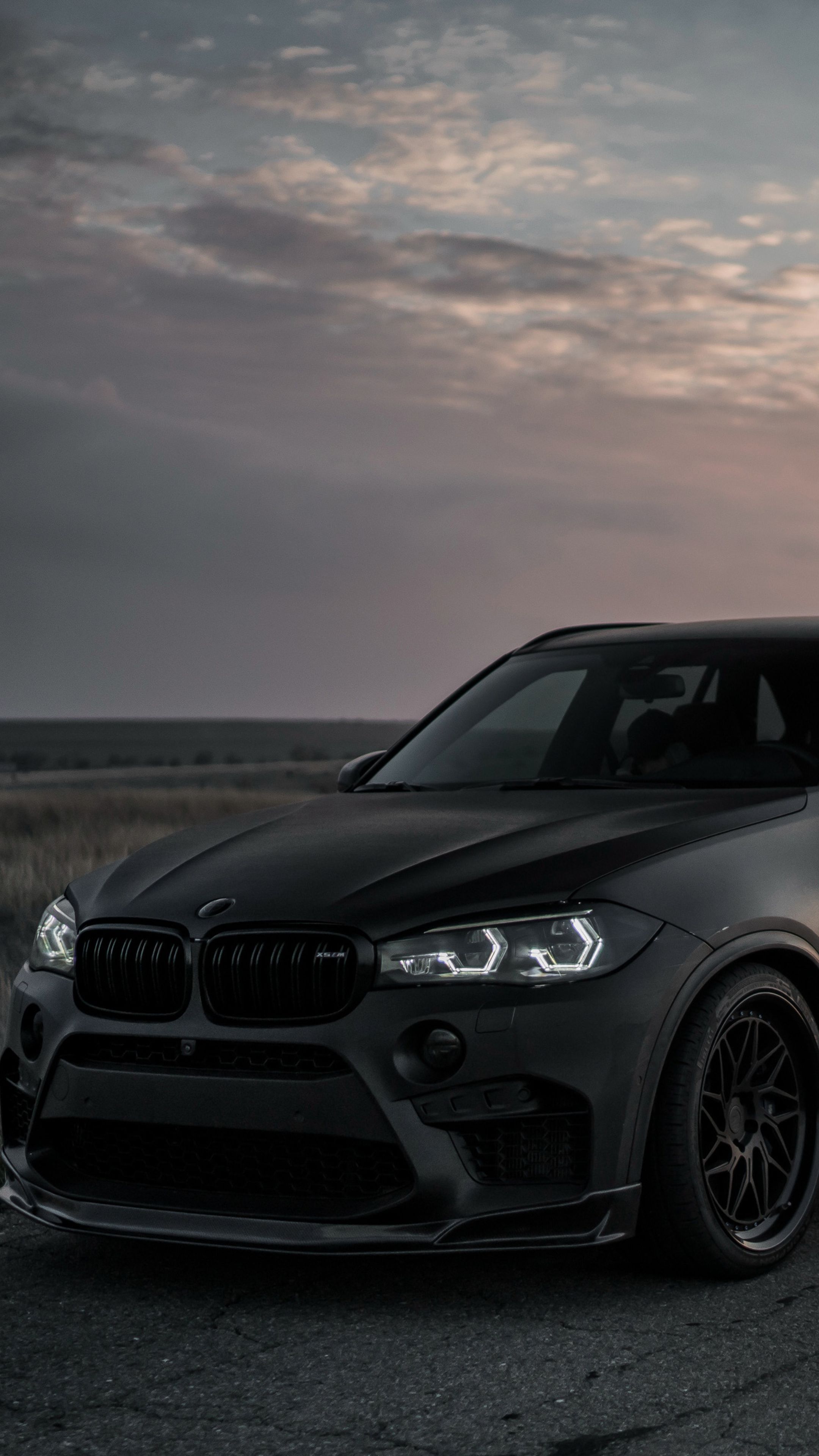 A black BMW X5M with the headlights on - BMW