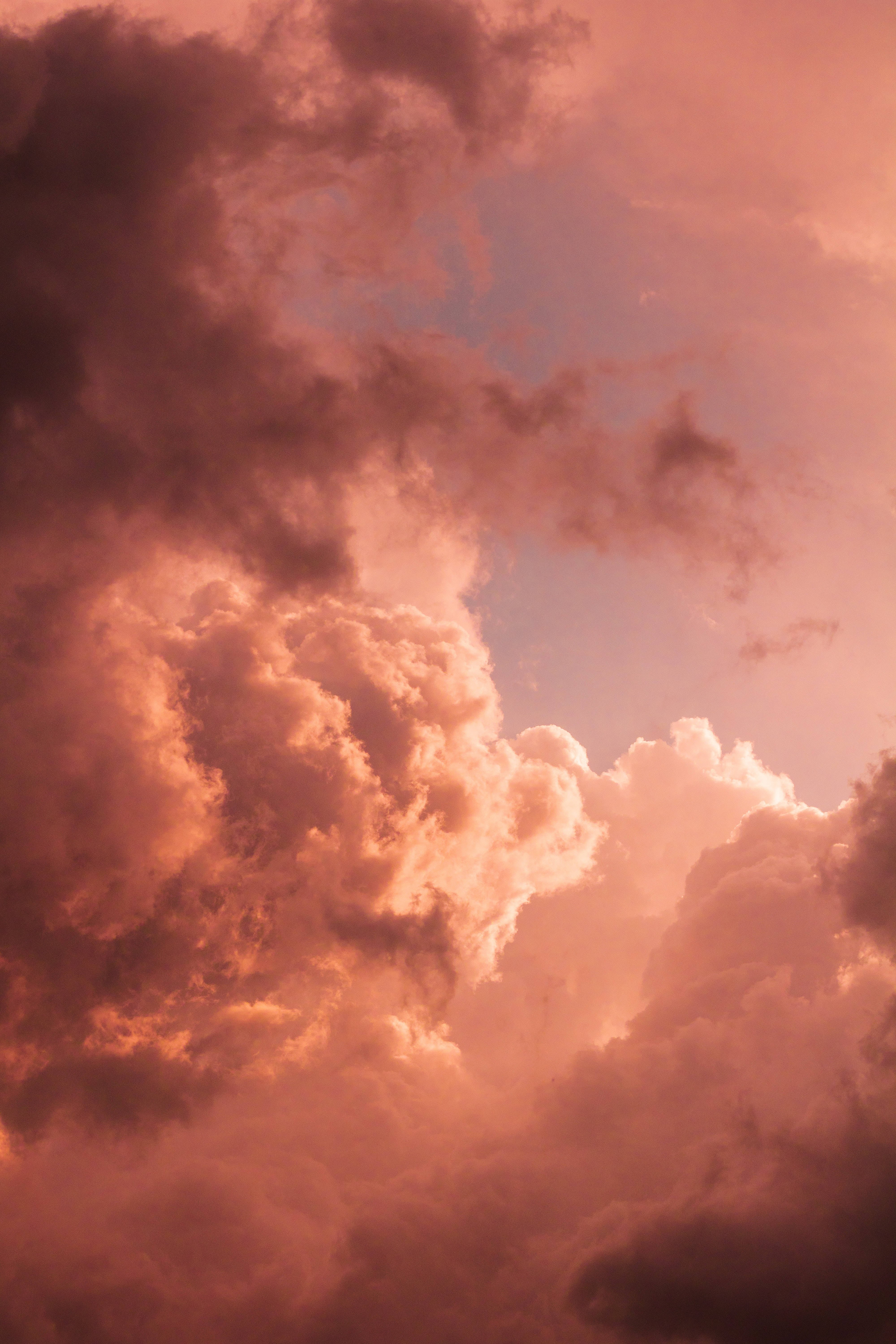 A sky with clouds of varying shades of pink and grey. - Pastel orange