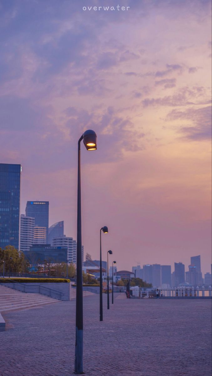A row of street lights on a walkway with a city skyline in the background - Anime city