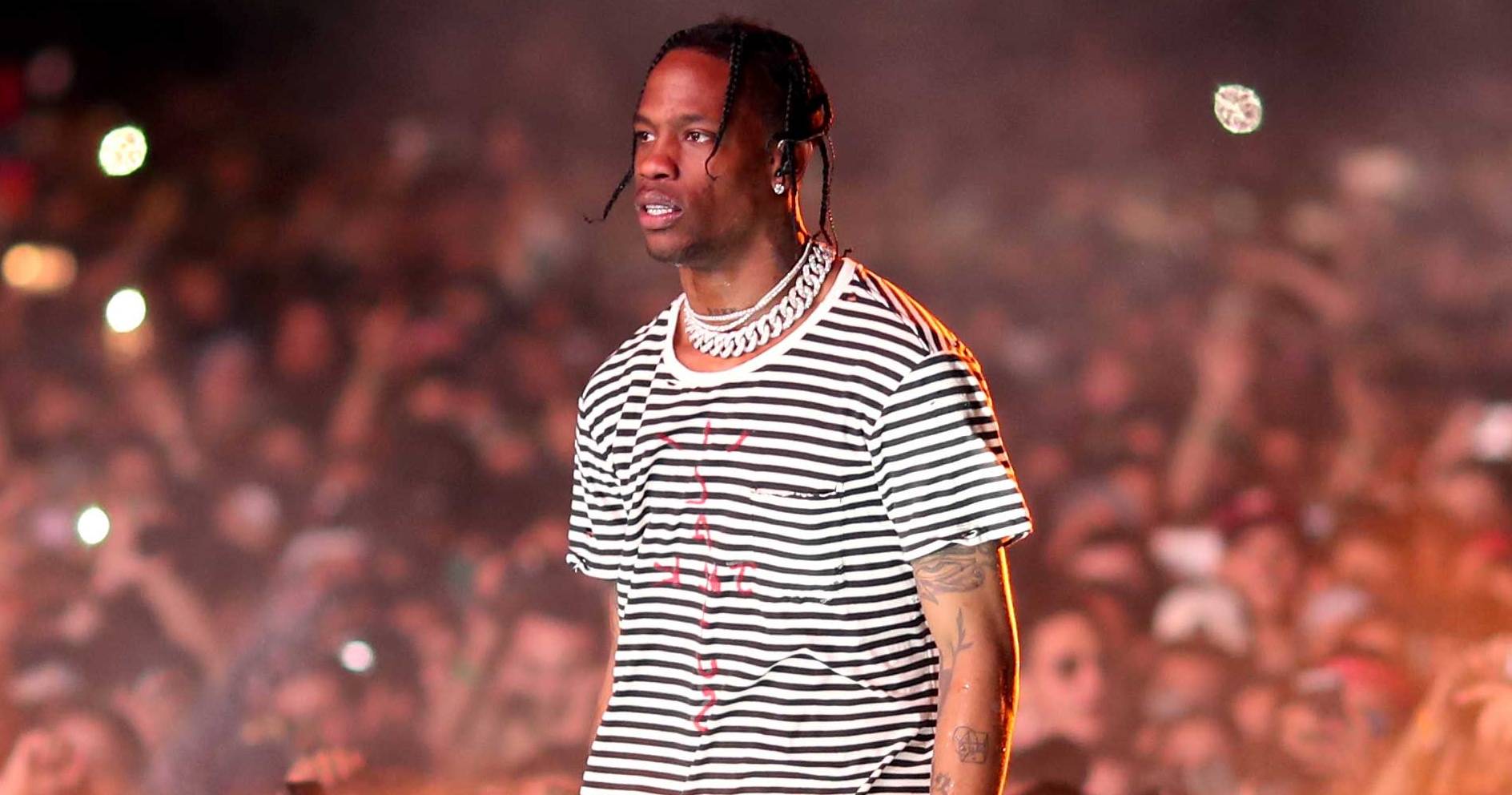 A man in striped shirt and headphones at concert - Travis Scott