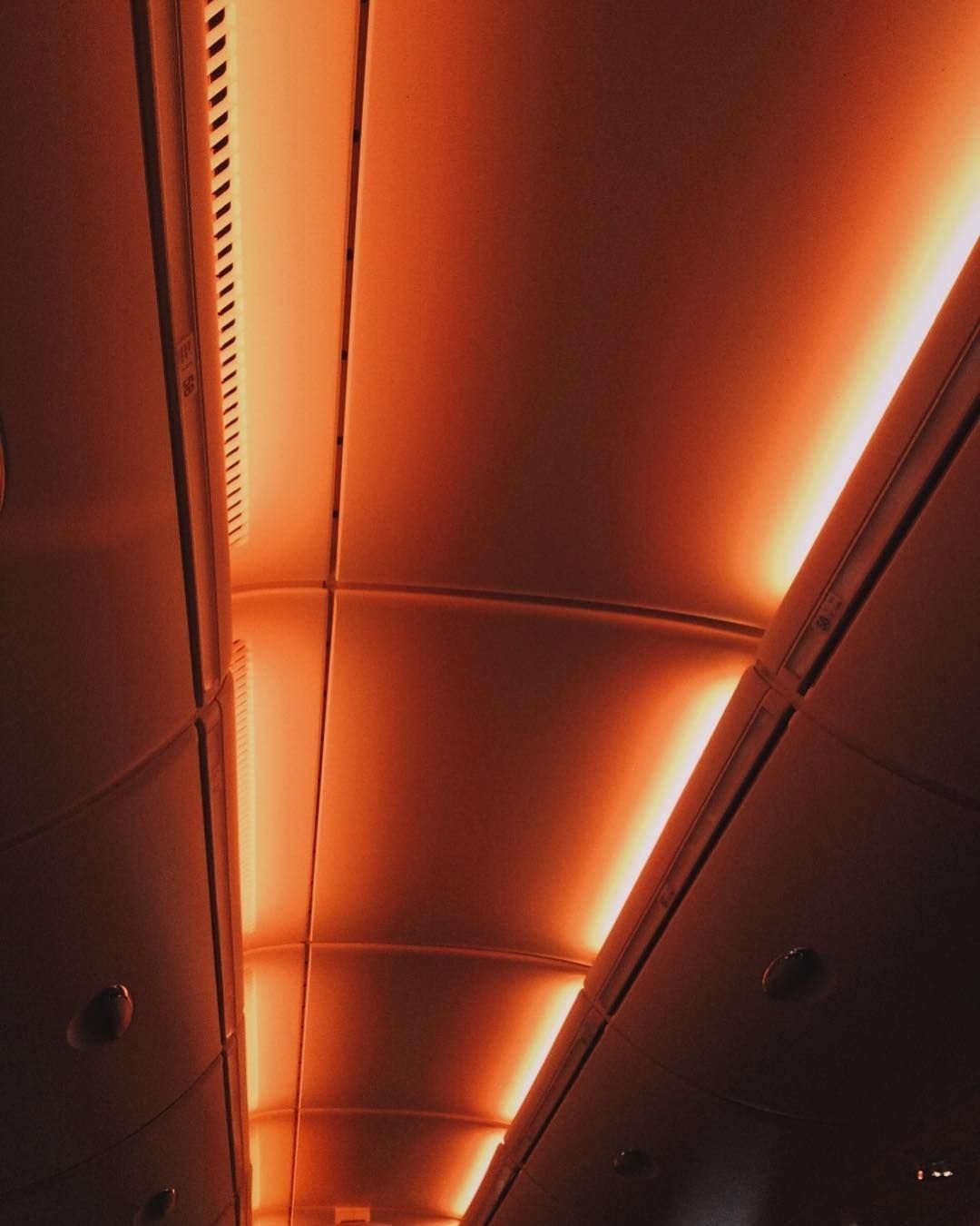 The ceiling of a train with orange lights. - Dark orange