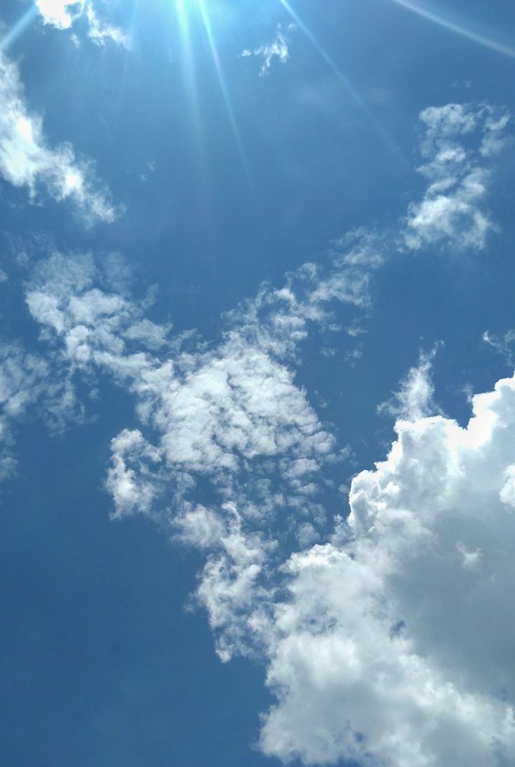 A plane flying through the blue sky with clouds - Sunlight