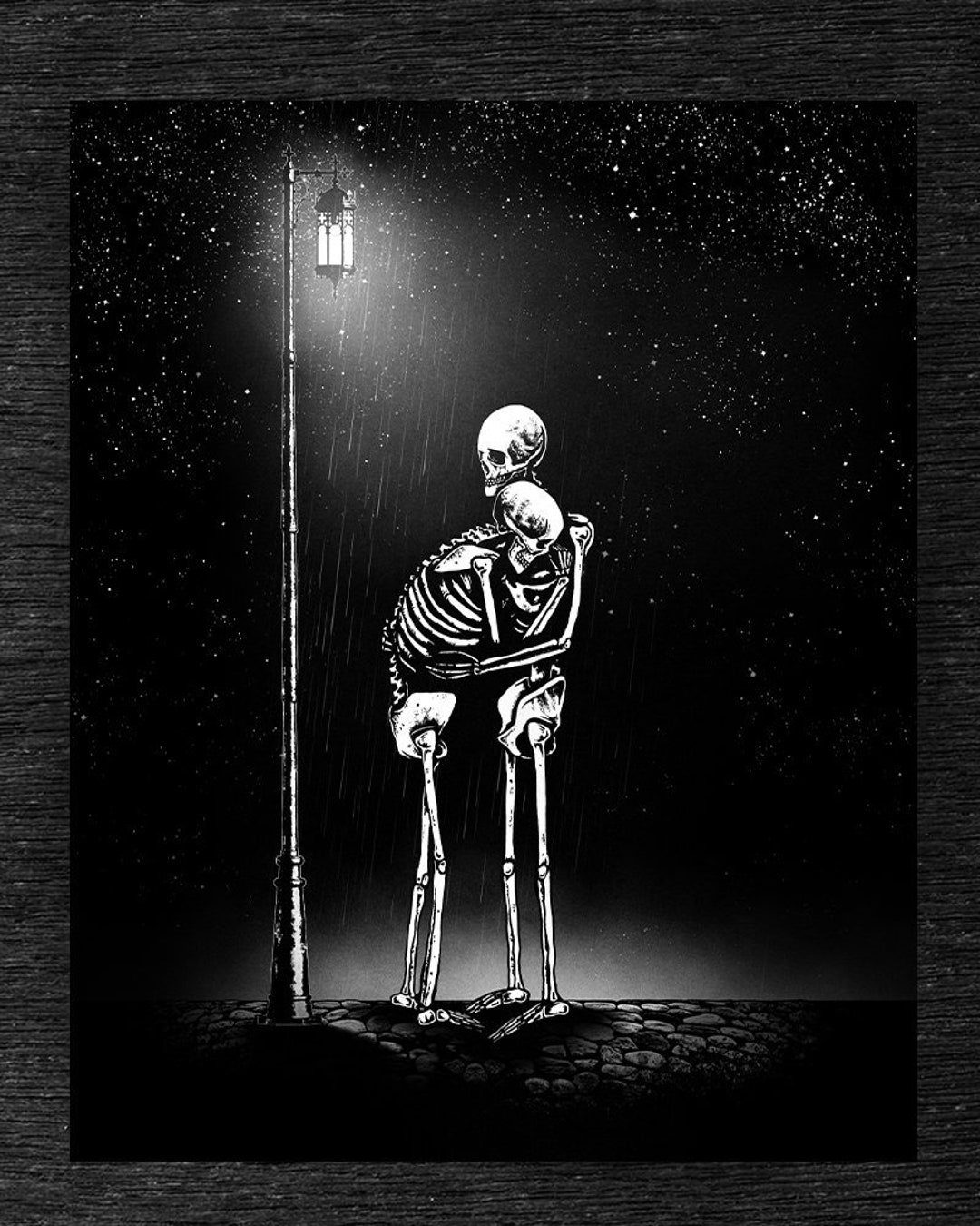 A black and white photo of two skeletons hugging under the street light - Gothic