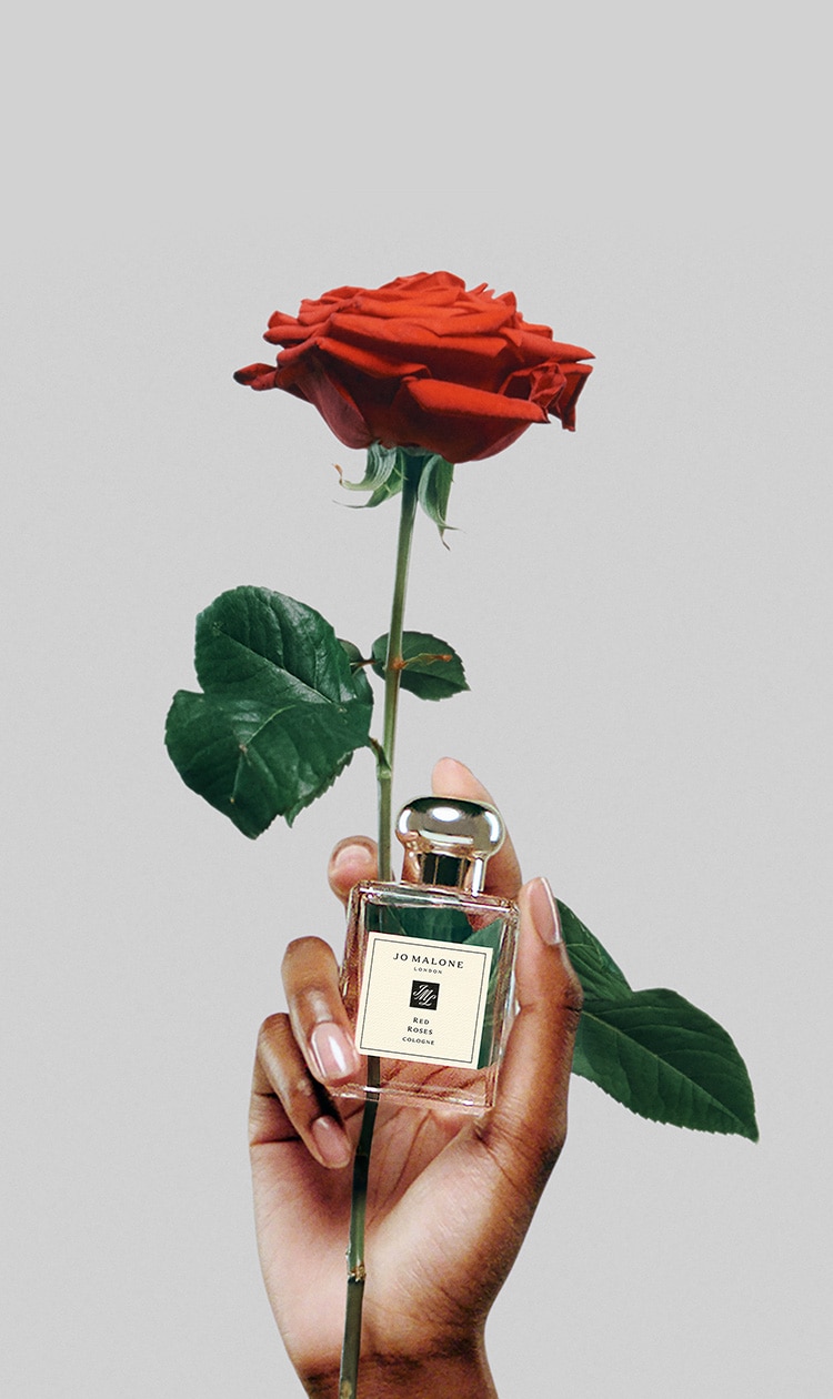 A hand holding a red rose and a bottle of Jo Malone perfume - Roses