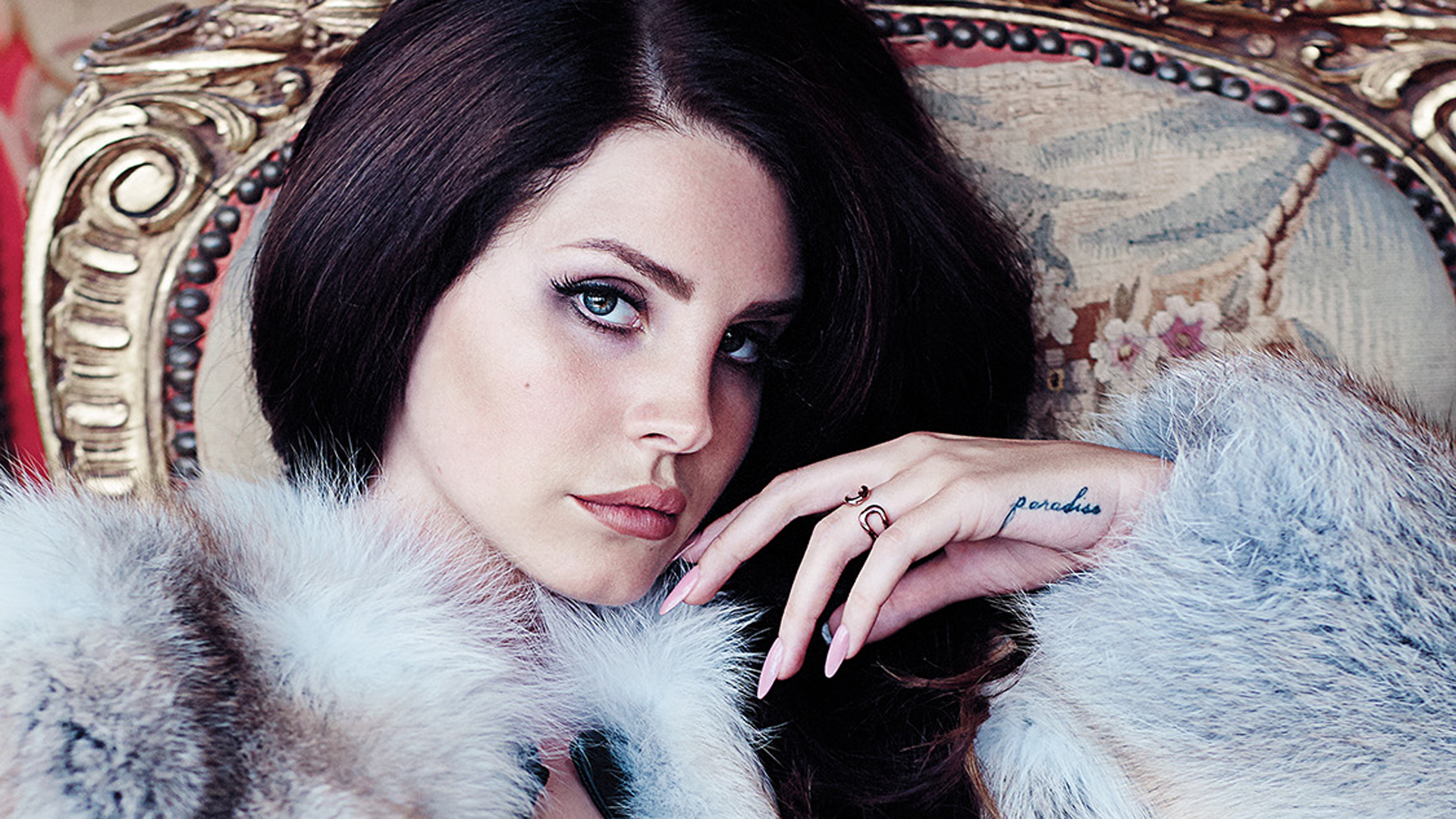 A woman with a fur coat and a tattoo on her hand. - Lana Del Rey