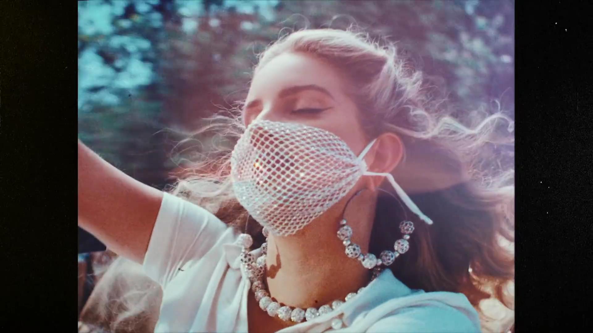 A woman wearing a white mask with a pearl necklace. - Lana Del Rey